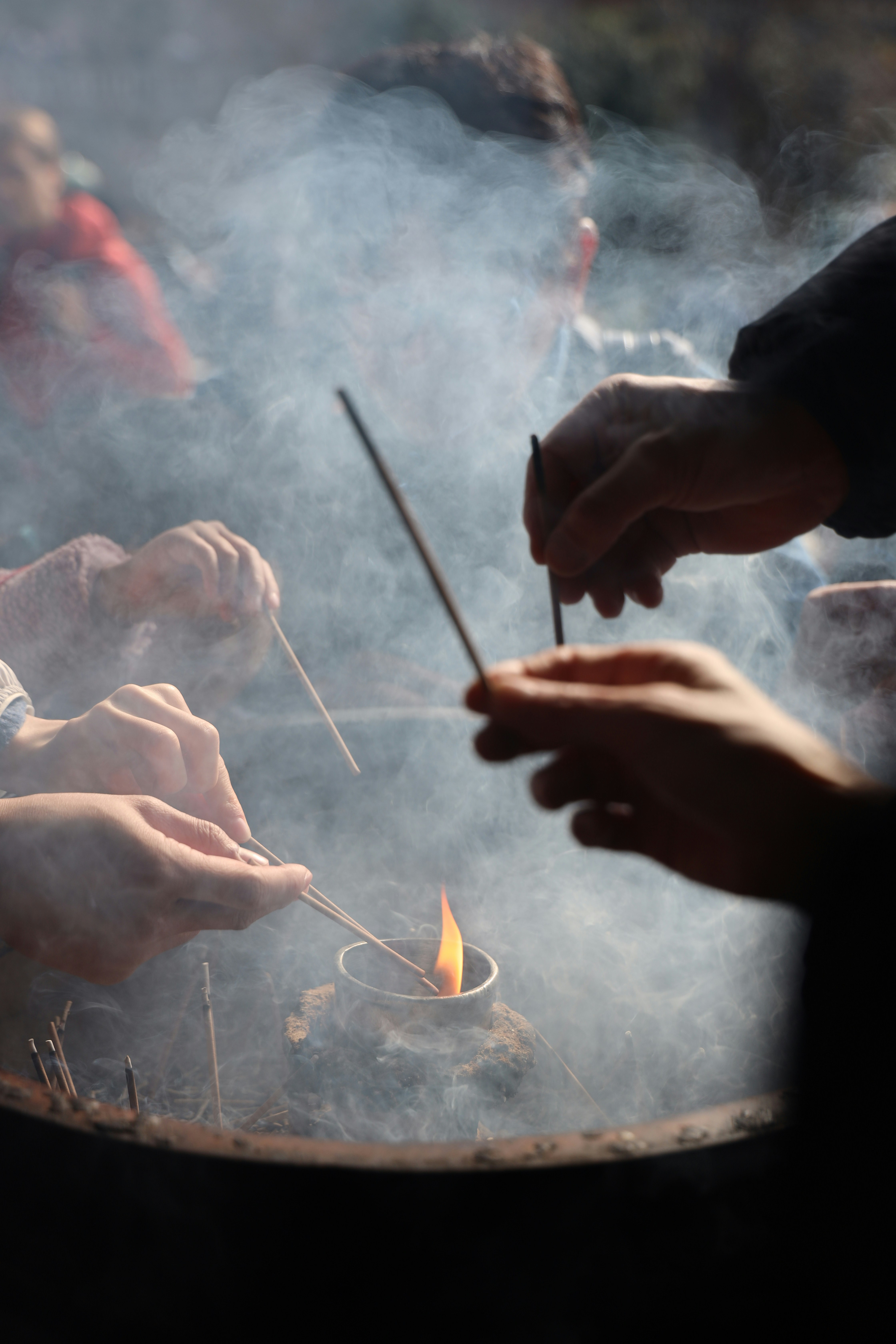 Pessoas acendendo bastões de incenso sobre a chama