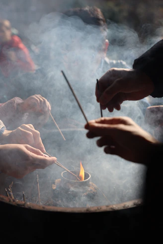 People lighting incense sticks over a flame