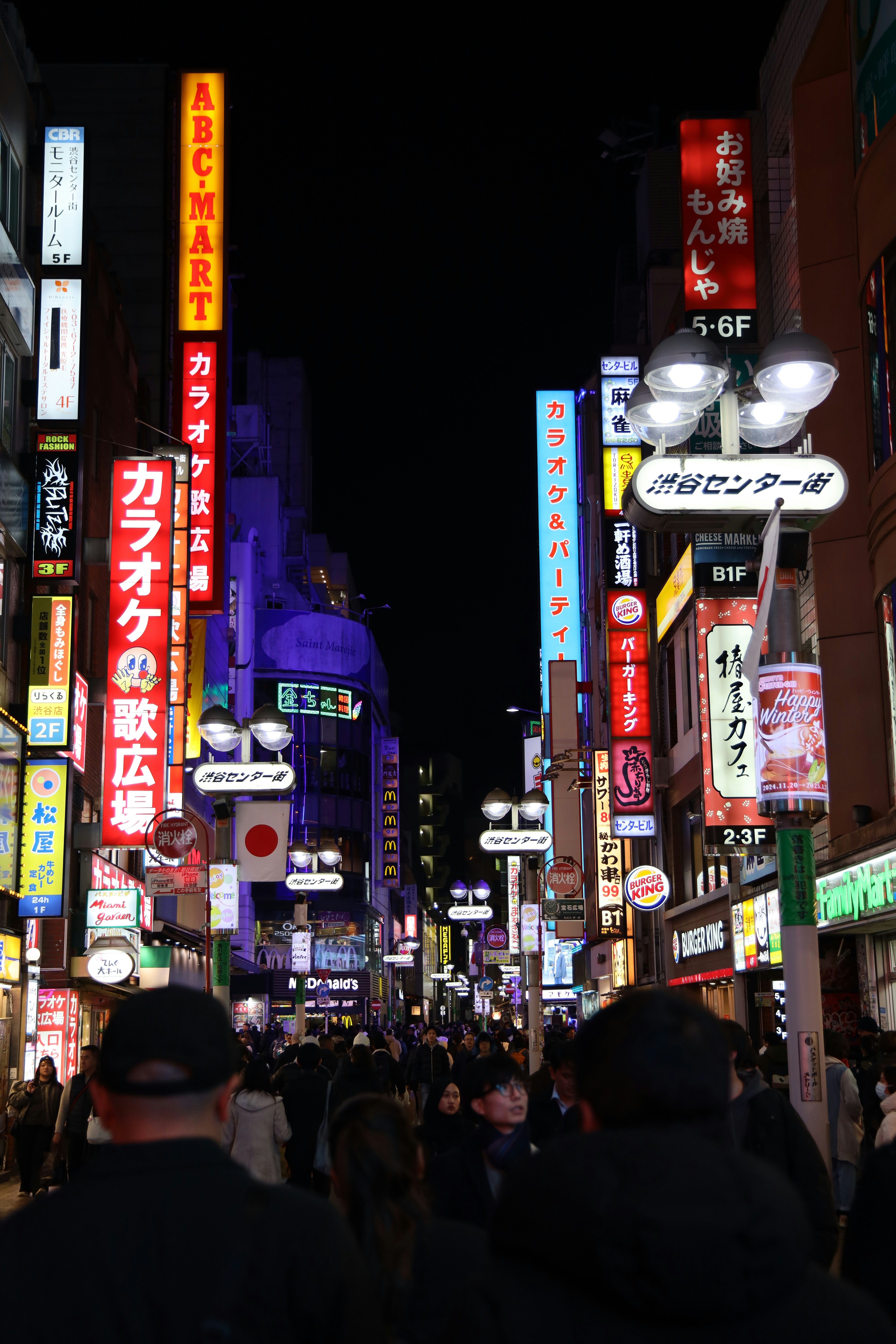Rua lotada com letreiros de neon à noite