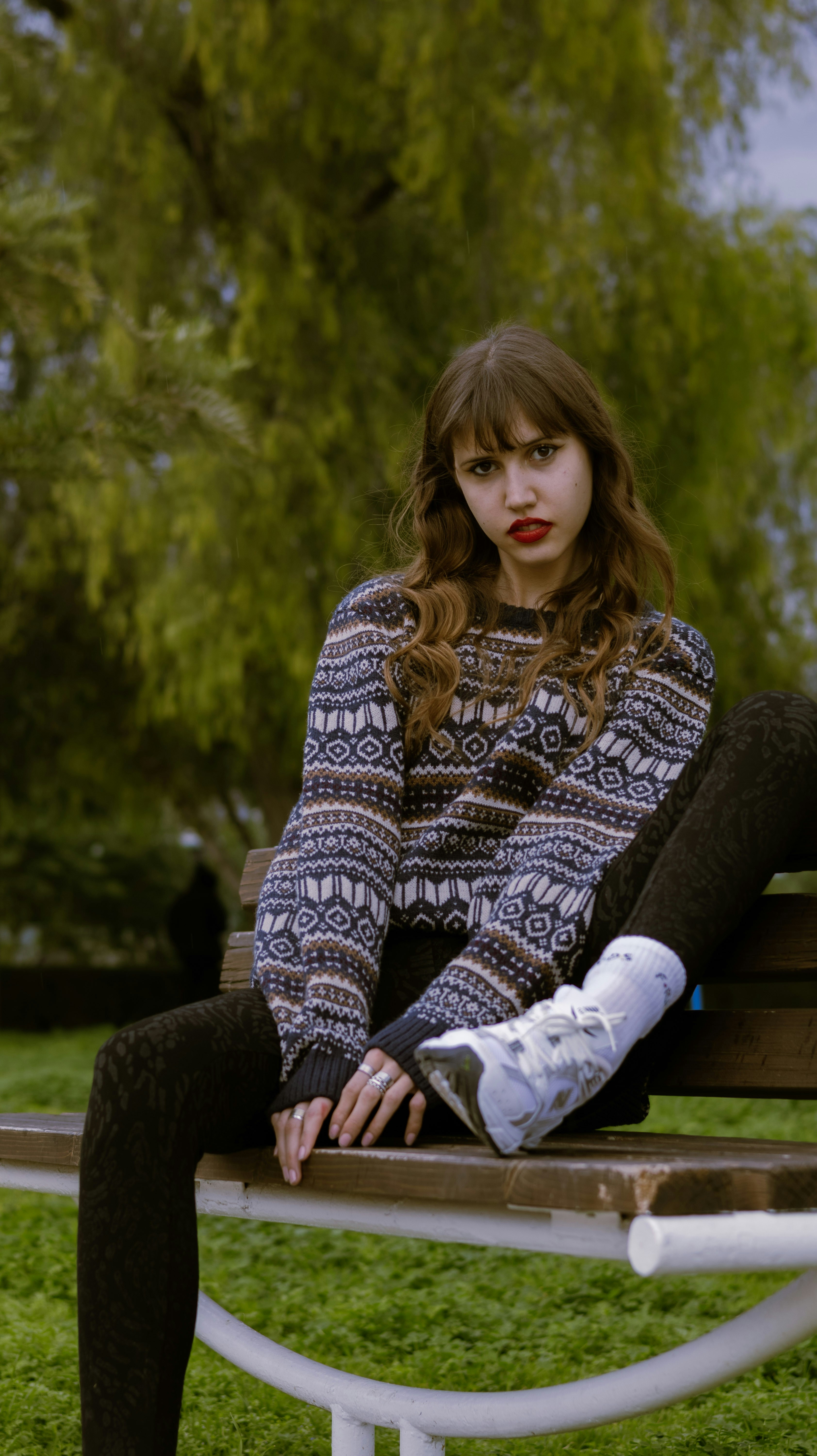 Young woman with red lipstick sitting on park bench