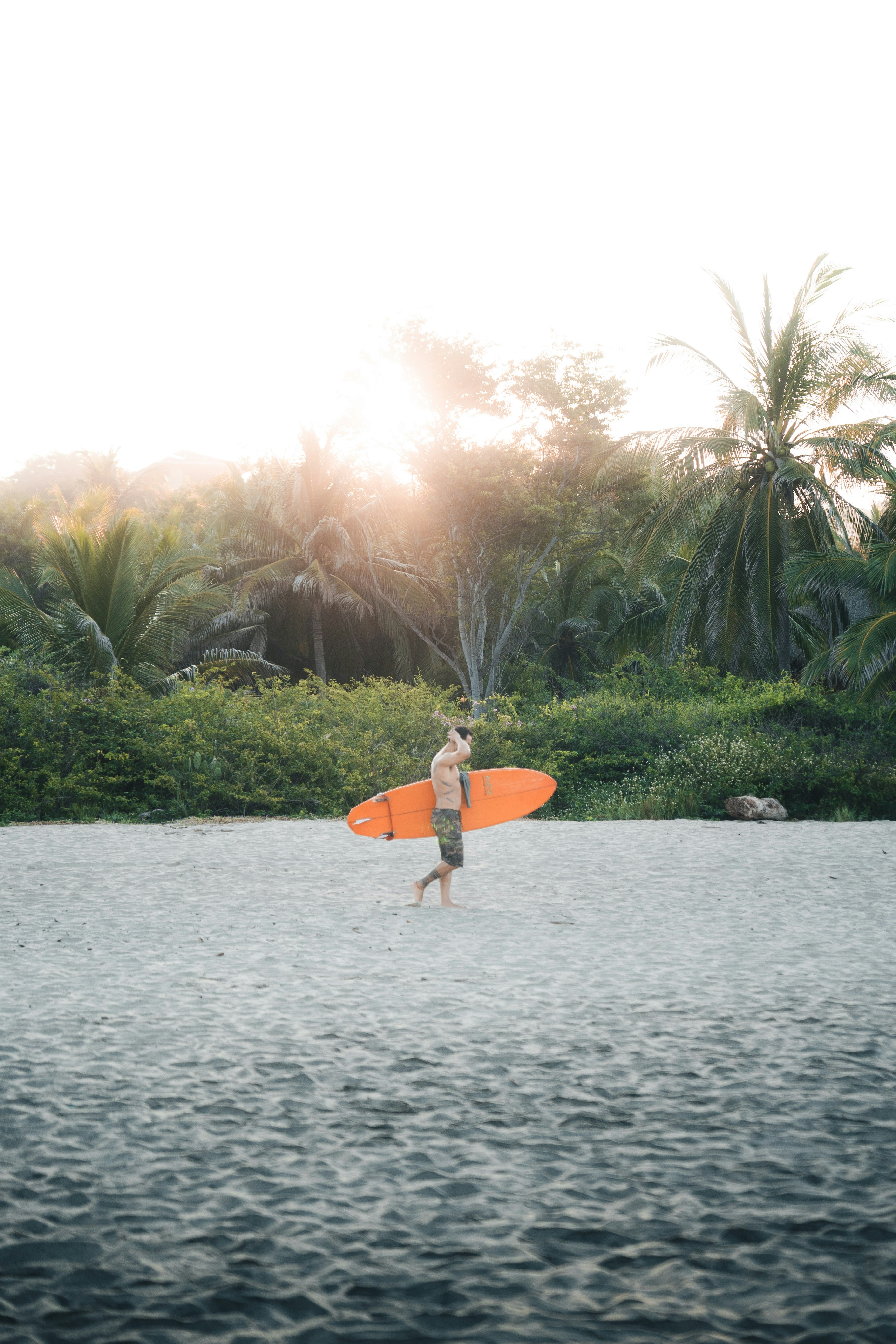 Man carrying surfboard on a sandy beach