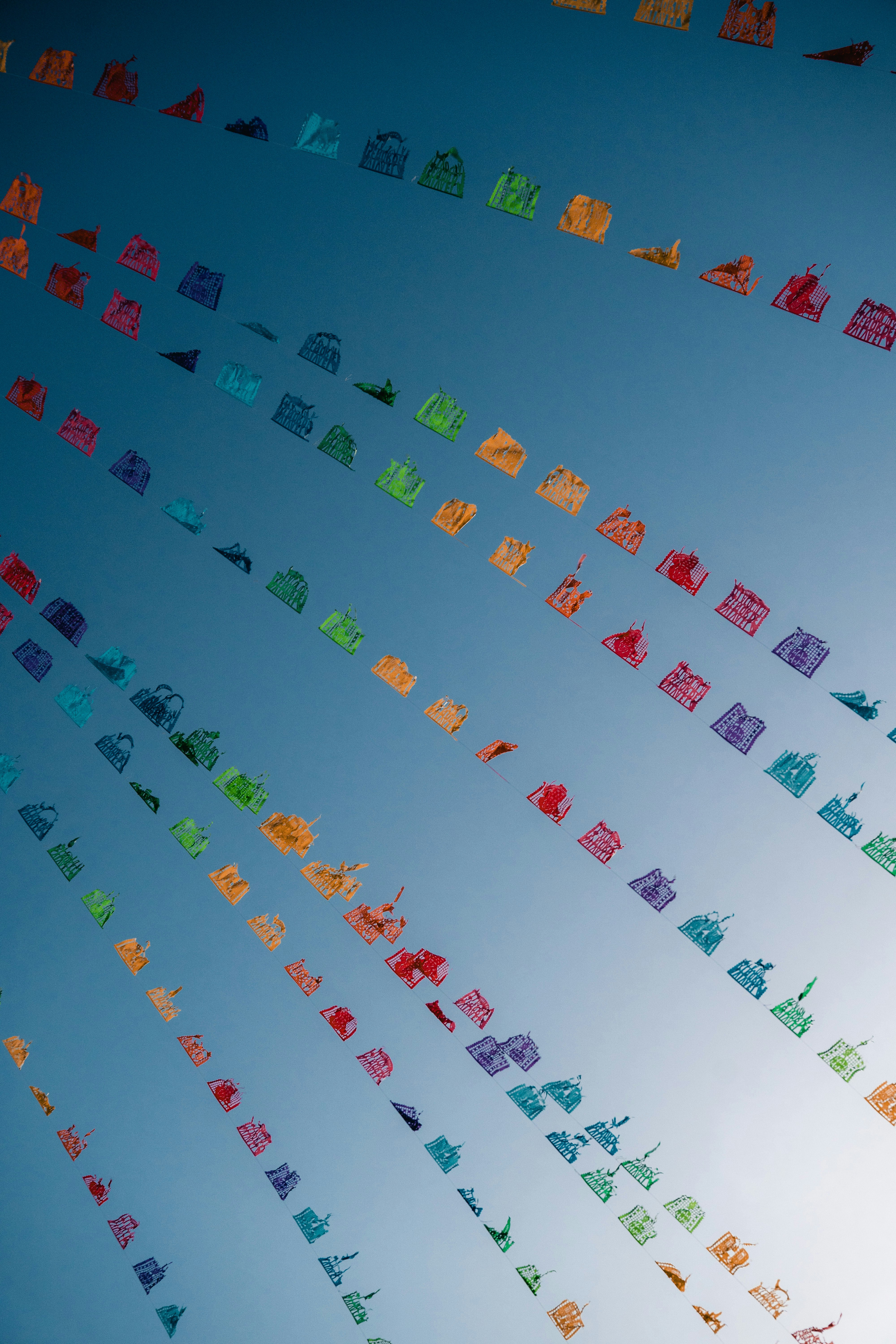 Colorful paper flags strung across a clear blue sky.