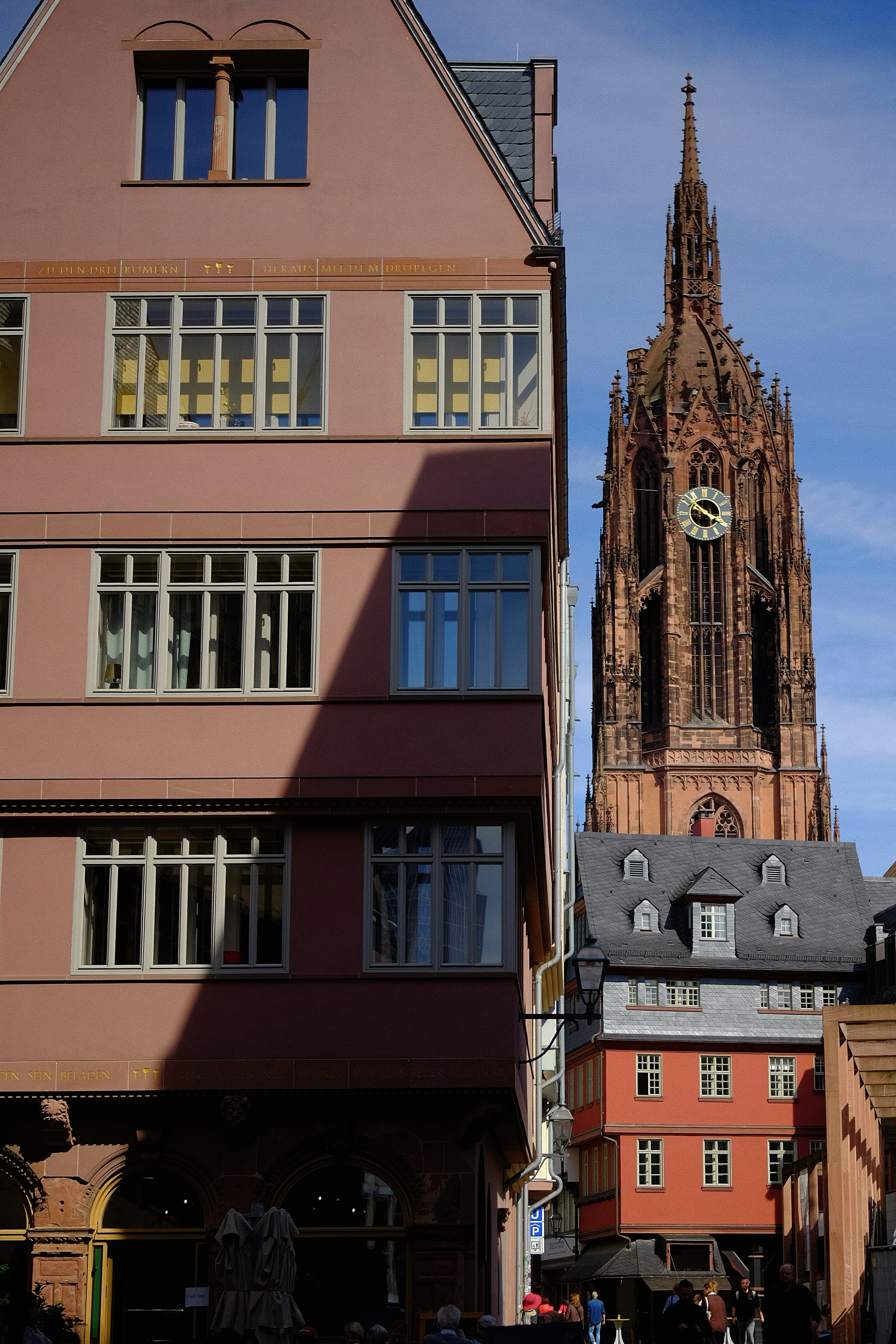 Hoher gotischer Kathedralturm hinter dem rosa Gebäude