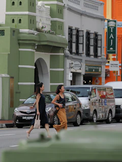 Two women cross a street in front of colorful buildings