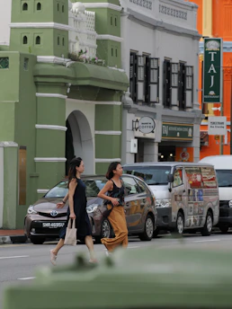 Two women cross a street in front of colorful buildings