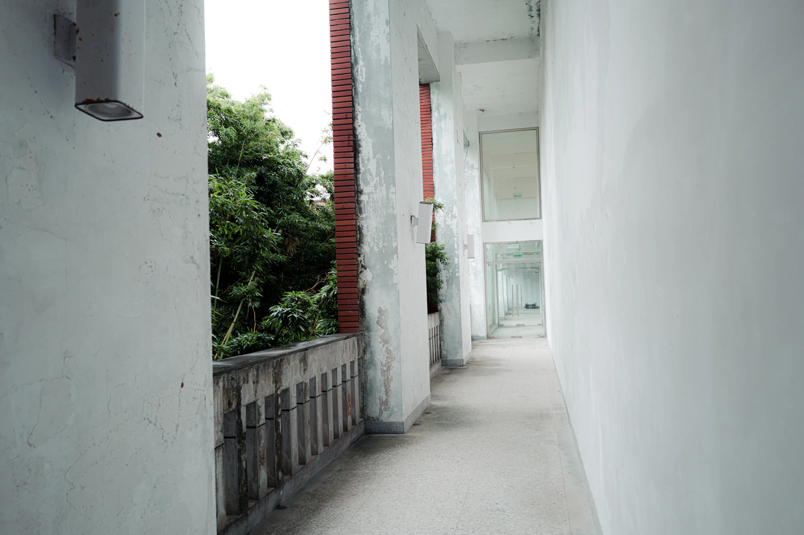 A narrow hallway with white walls and green trees outside