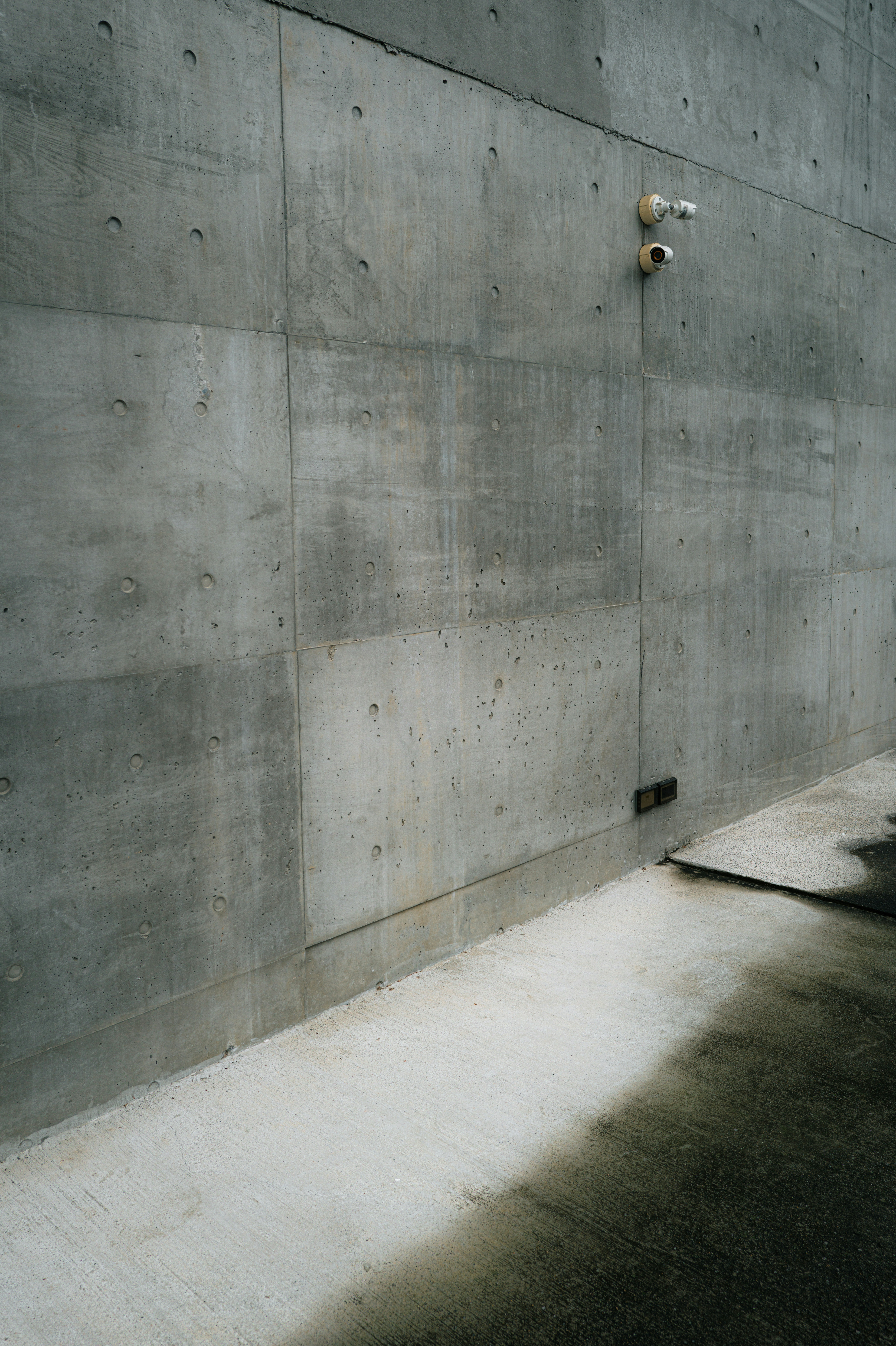 Uma parede moderna de concreto com câmeras de segurança.