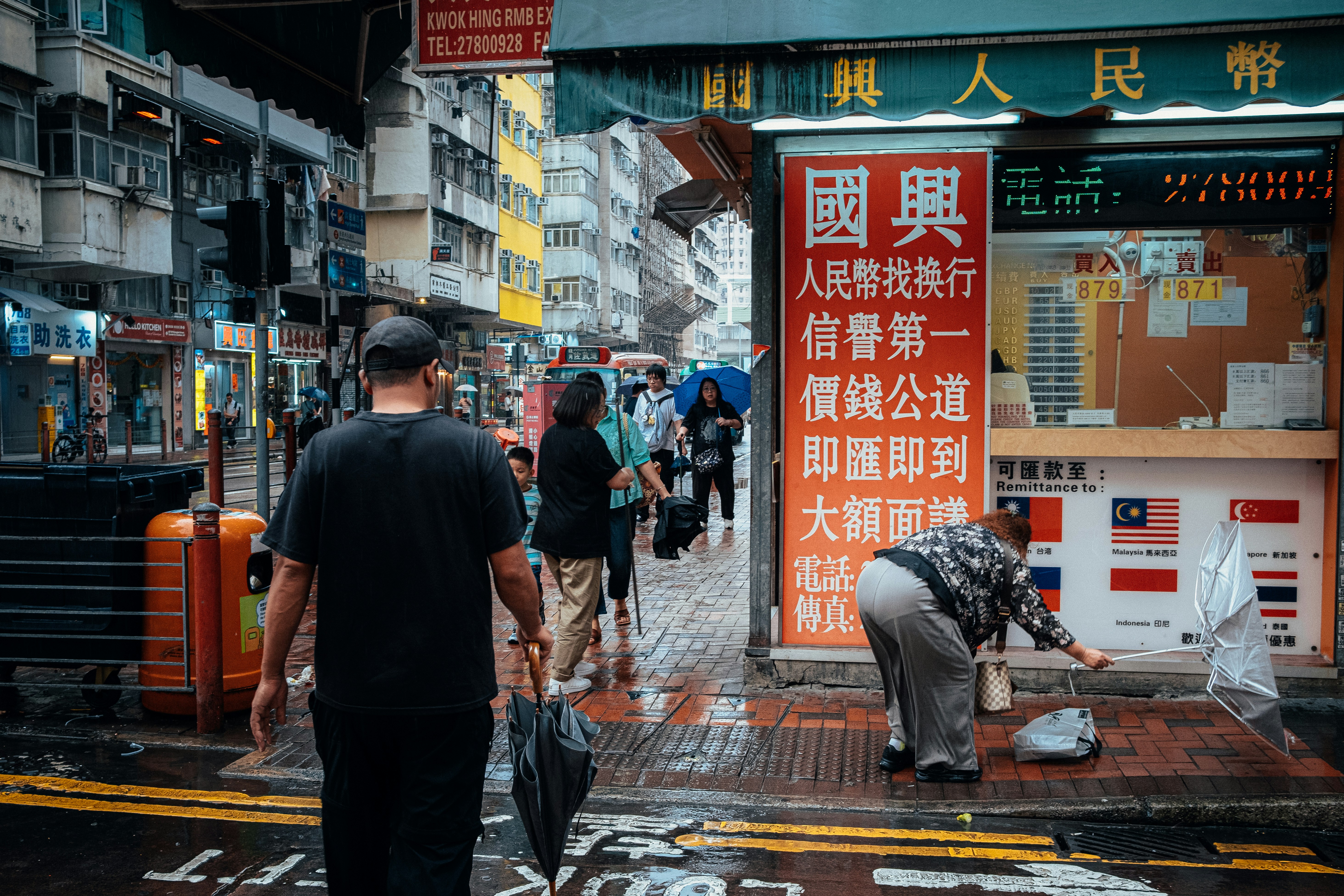 People walking on a wet city street with signs