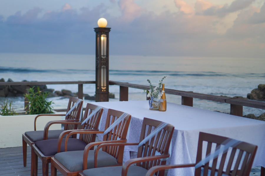 Elegant dining table set for two on the shore at sunset, waves in the background