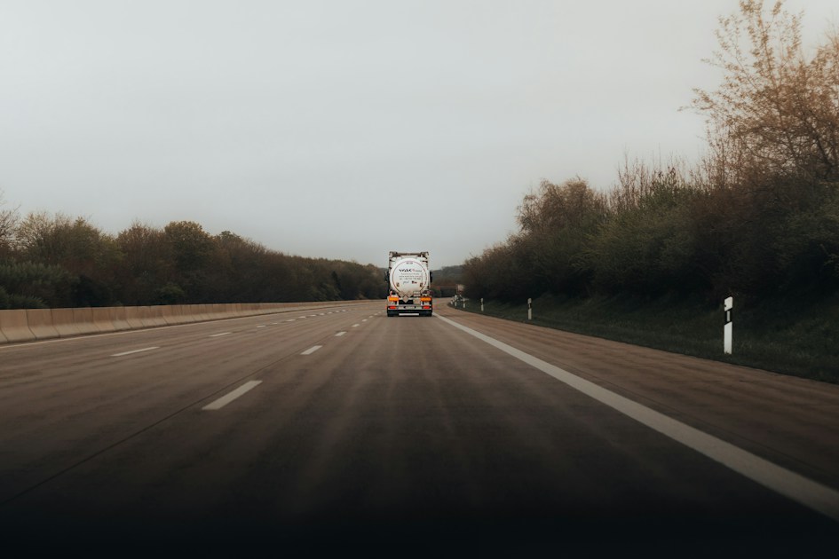 Truck driving on a highway with trees alongside