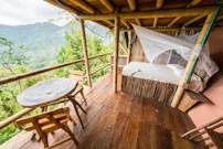 Bamboo hut with bed and table overlooking lush mountains