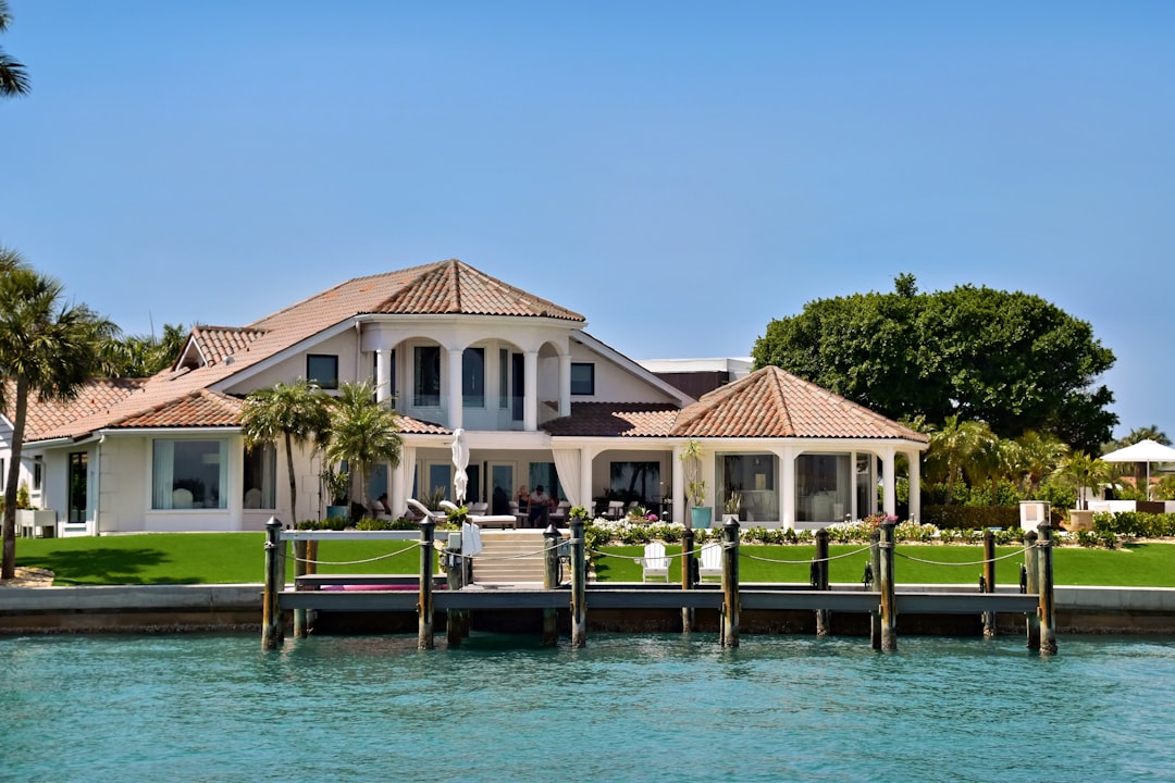 Luxury waterfront property with dock and clear blue water reflecting a Florida sunset