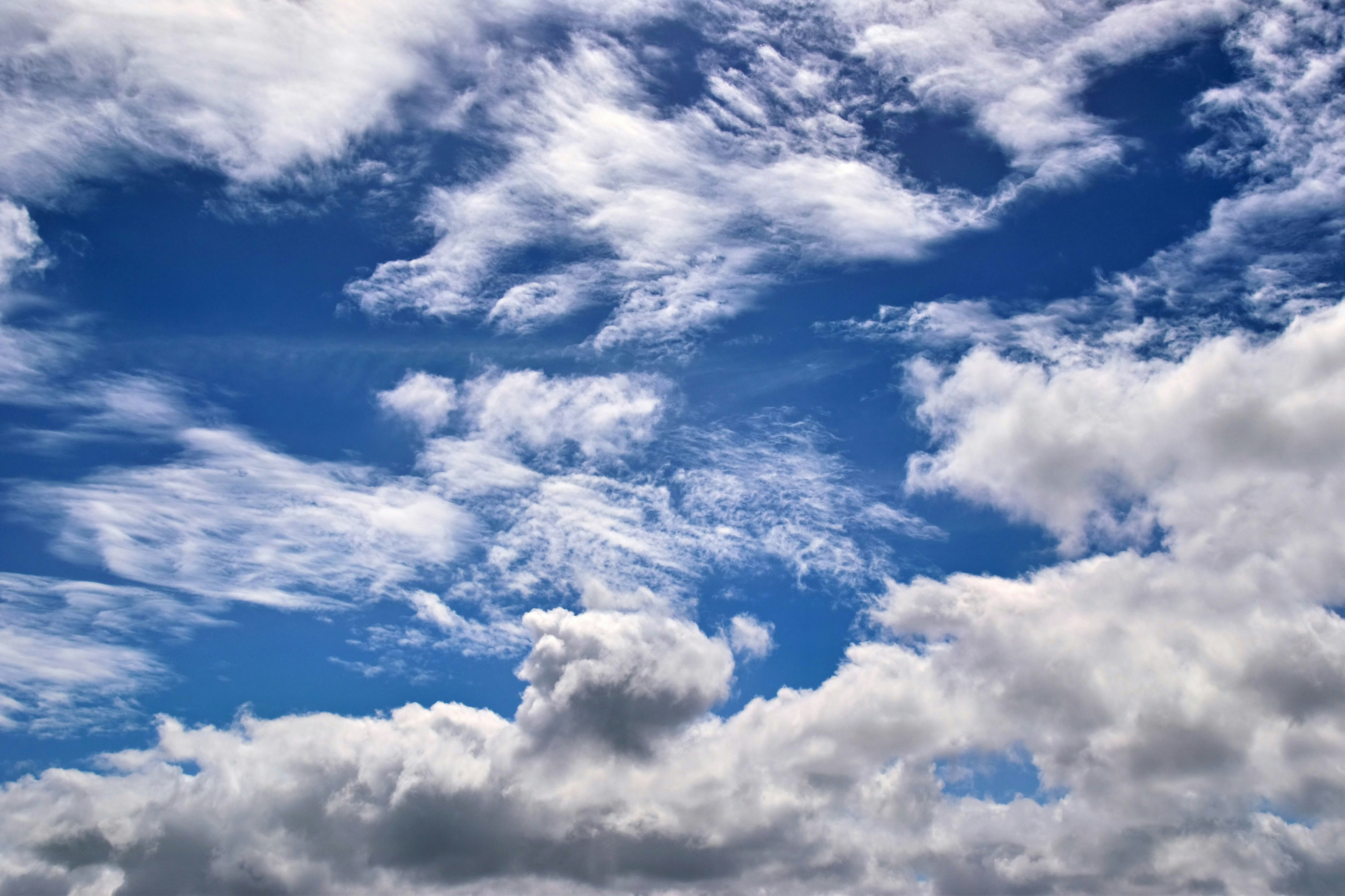 Fluffy white clouds drift across a bright blue sky