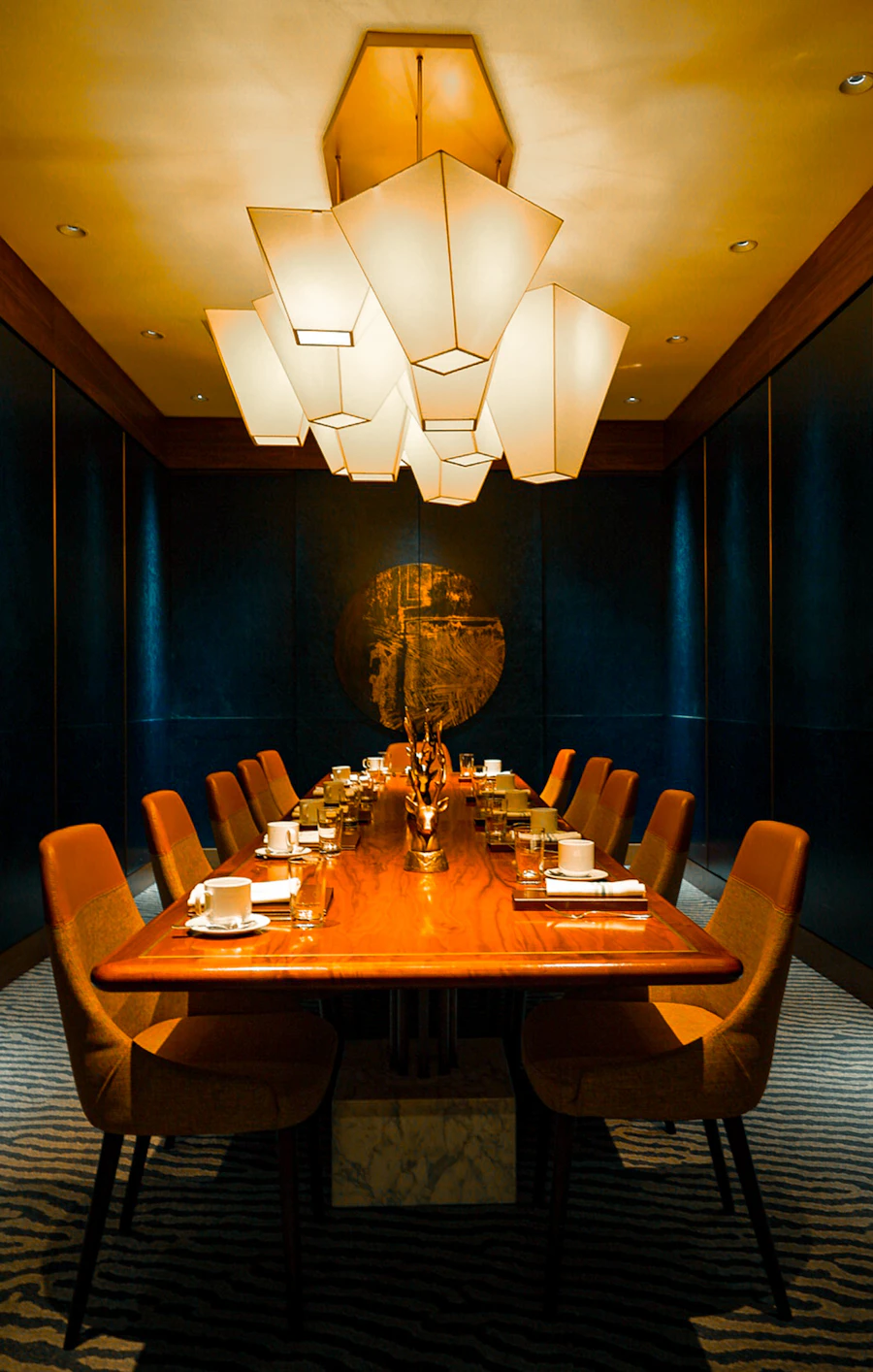 The private dining room: a long table under a lantern chandelier, set for fourteen