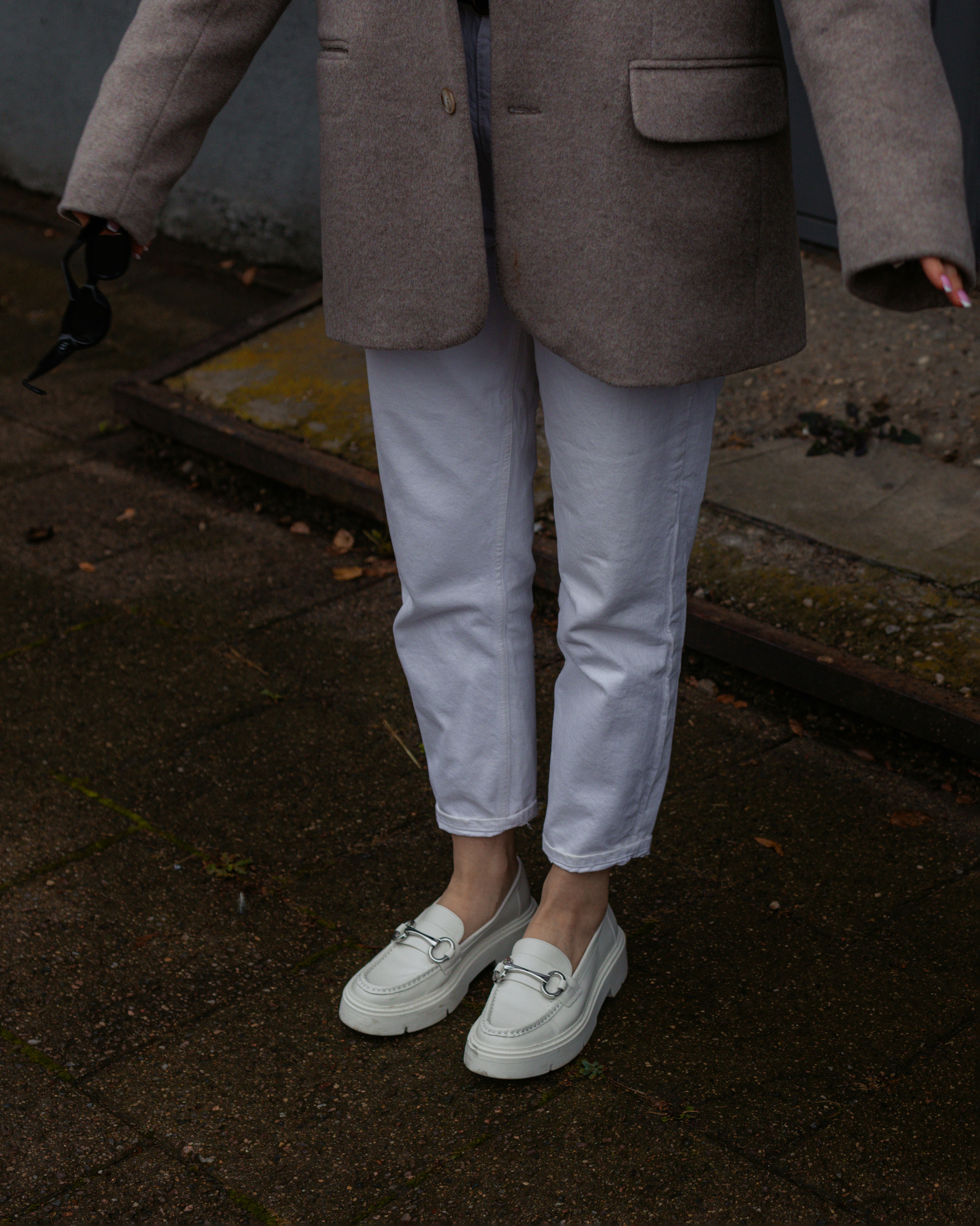 A person wearing white jeans and loafers