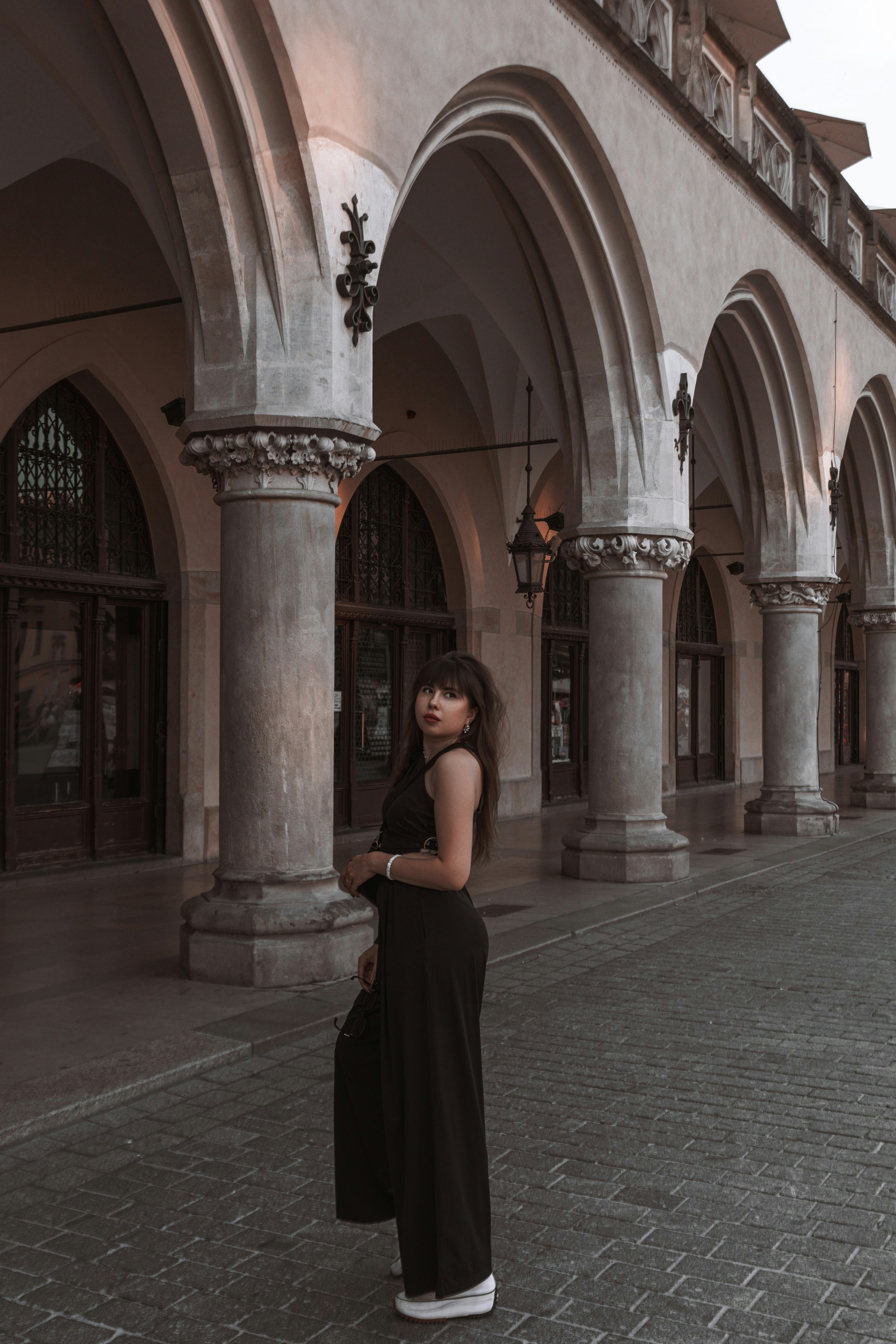 Woman in black standing near arched building