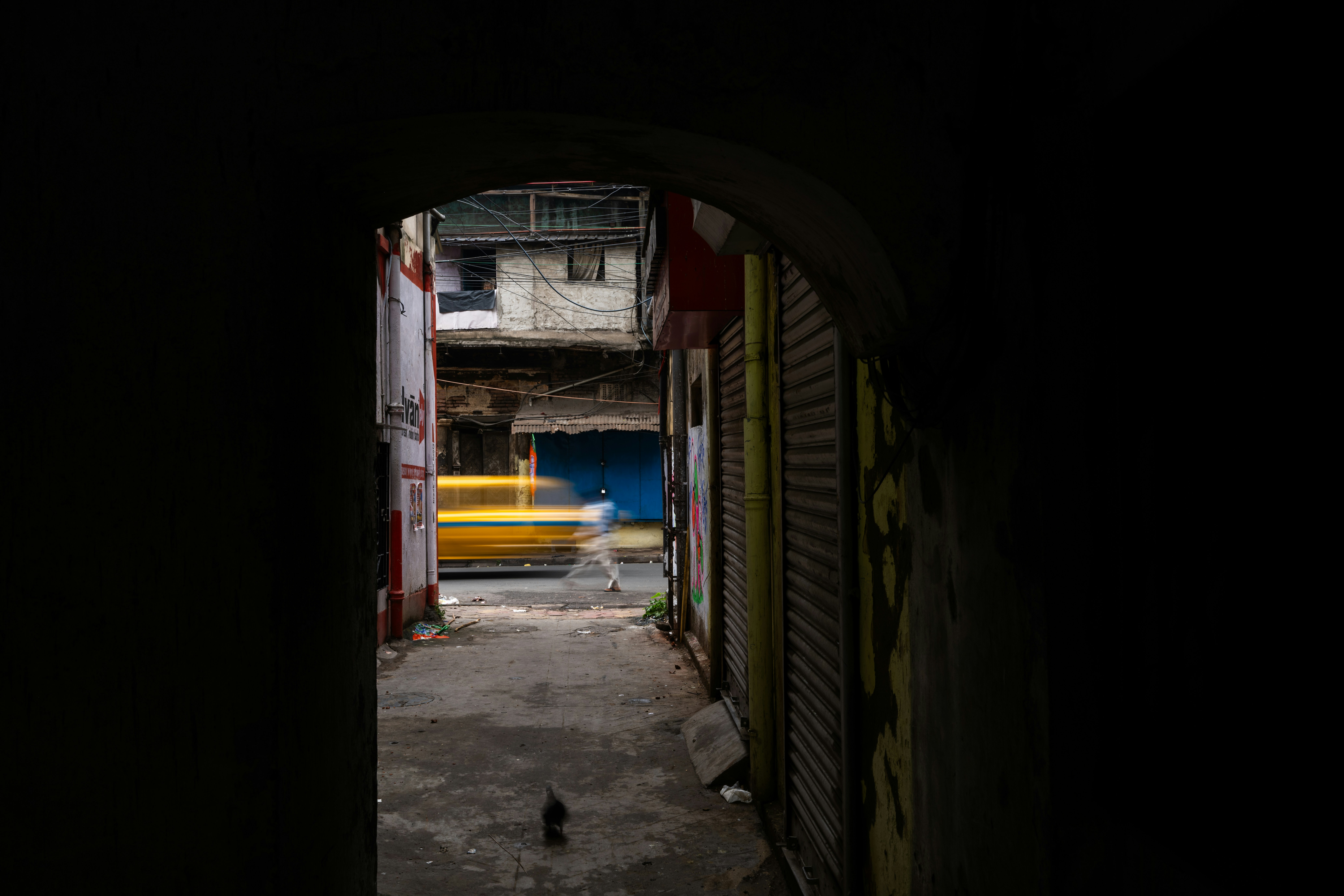 Yellow taxi blurred in motion down alleyway.