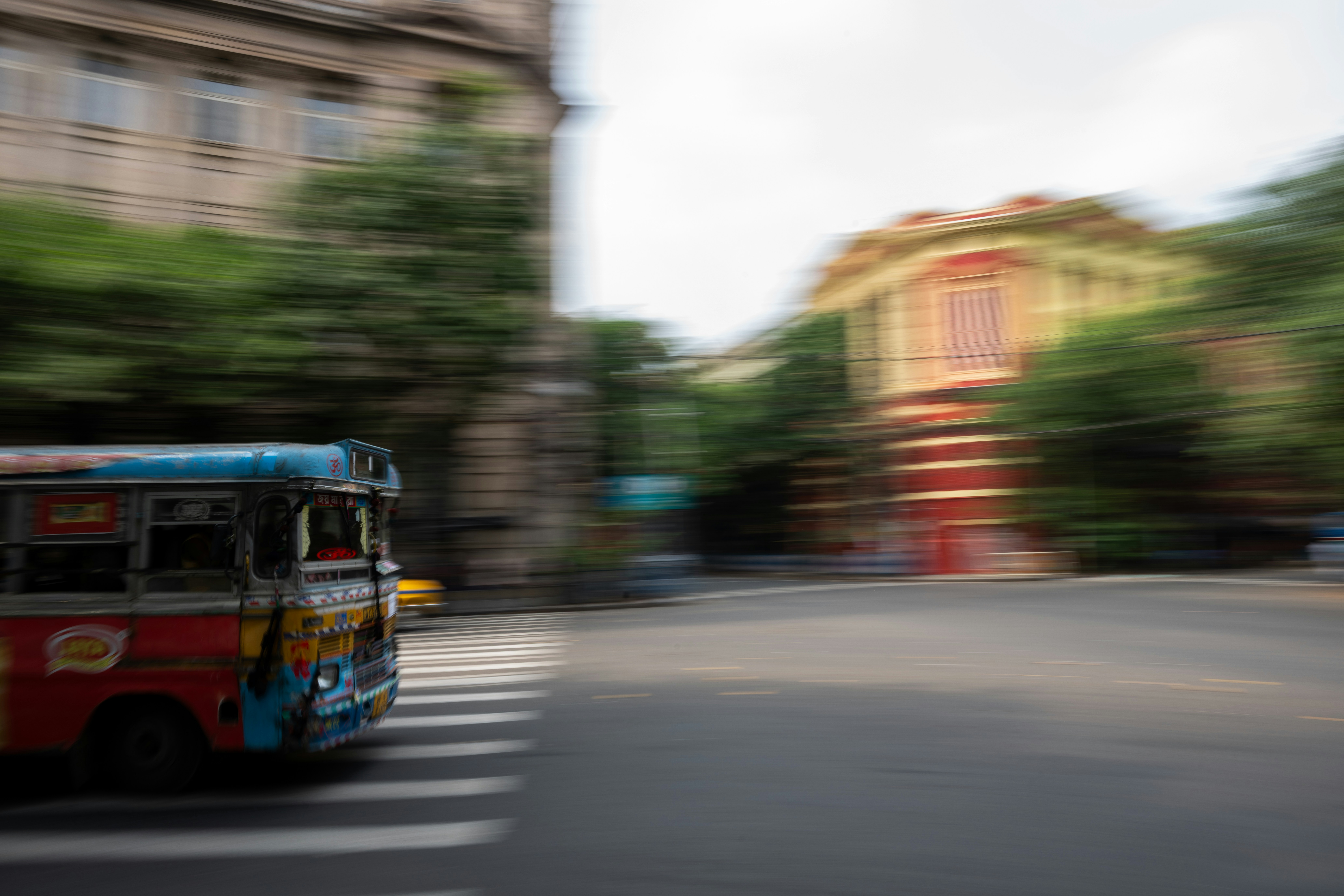 A colorful bus moves quickly through a city street.