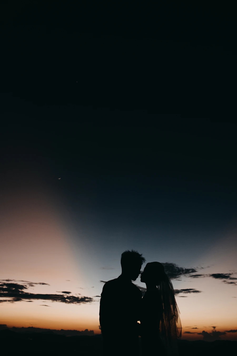 Couple standing against a dramatic sunset