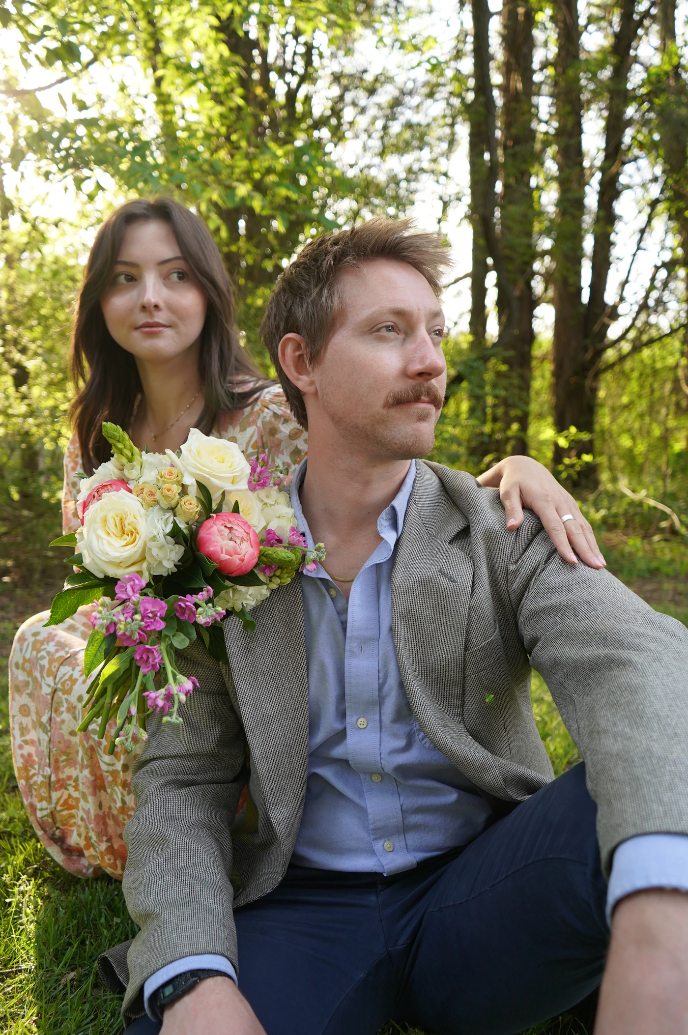 Couple holding a bouquet together in a lush green woodland
