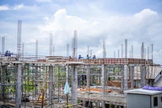 Construction workers building a structure under a cloudy sky.