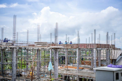 Construction workers building a structure under a cloudy sky.