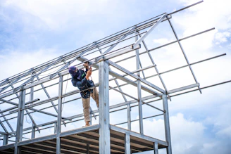 Construction worker assembling metal frame against sky