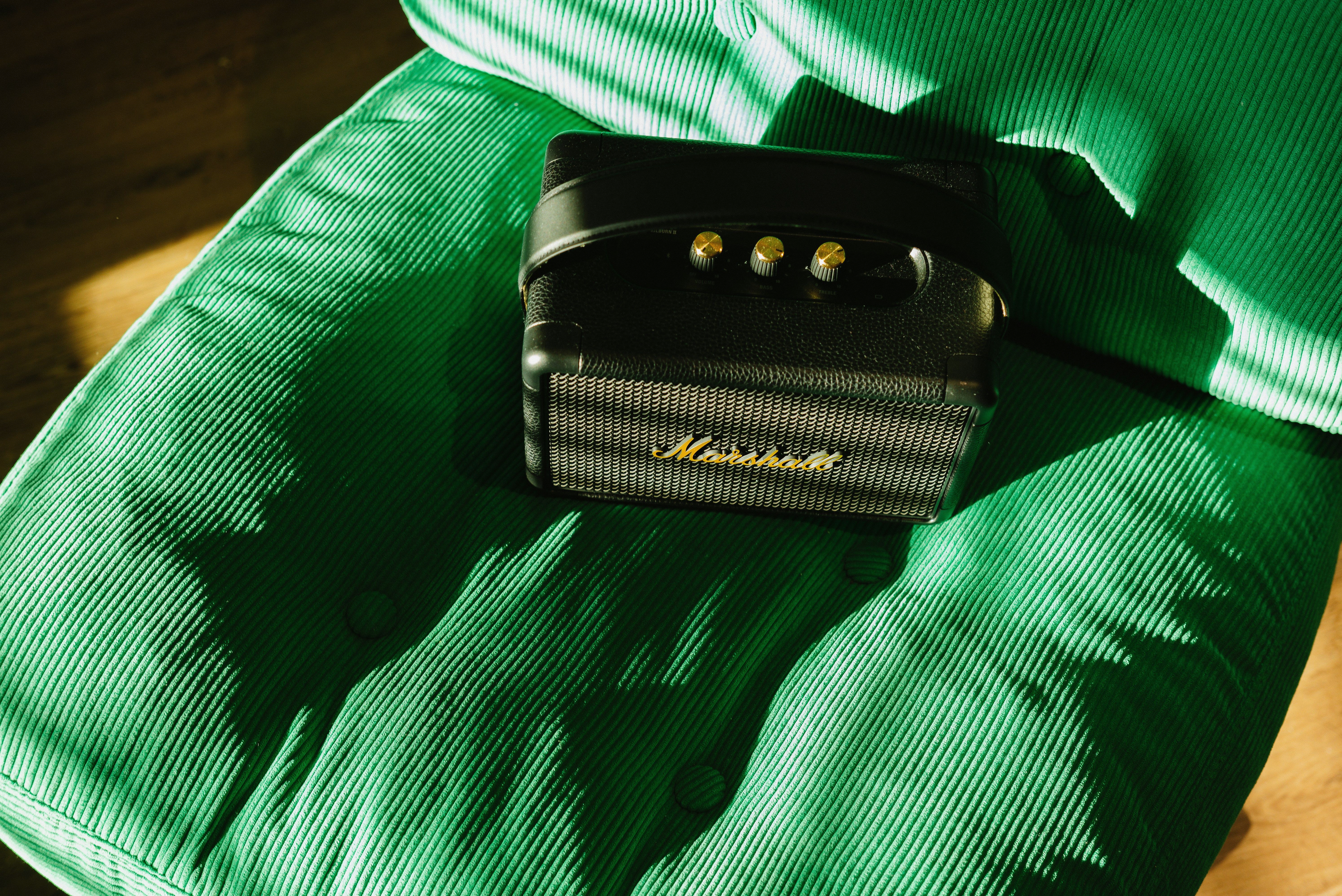 Amplificateur marshall noir sur une chaise en velours côtelé verte