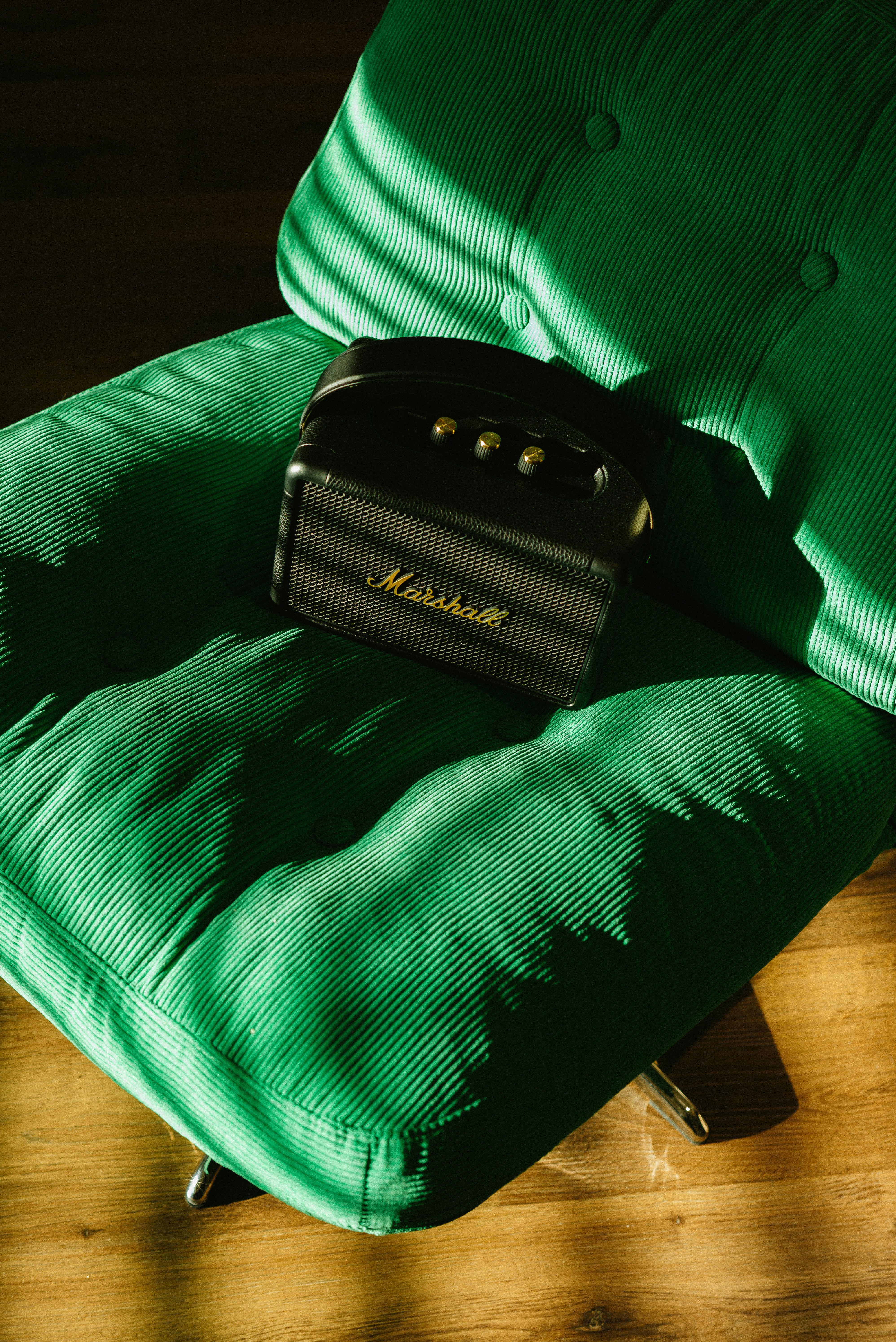 Black marshall amplifier rests on a green chair.