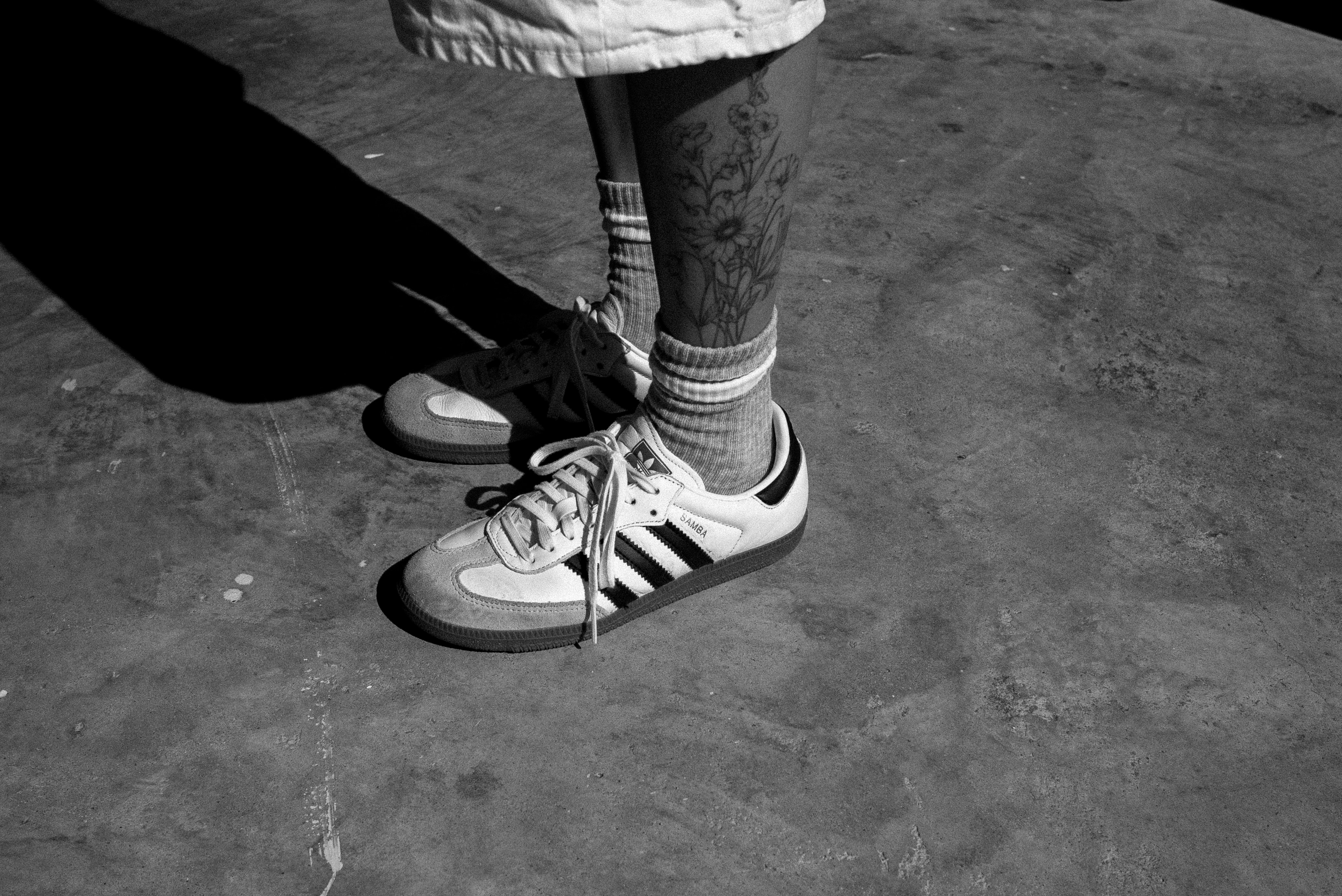 Person's legs with tattoos and sneakers on pavement. photo  Free Fashion  Image on Unsplash