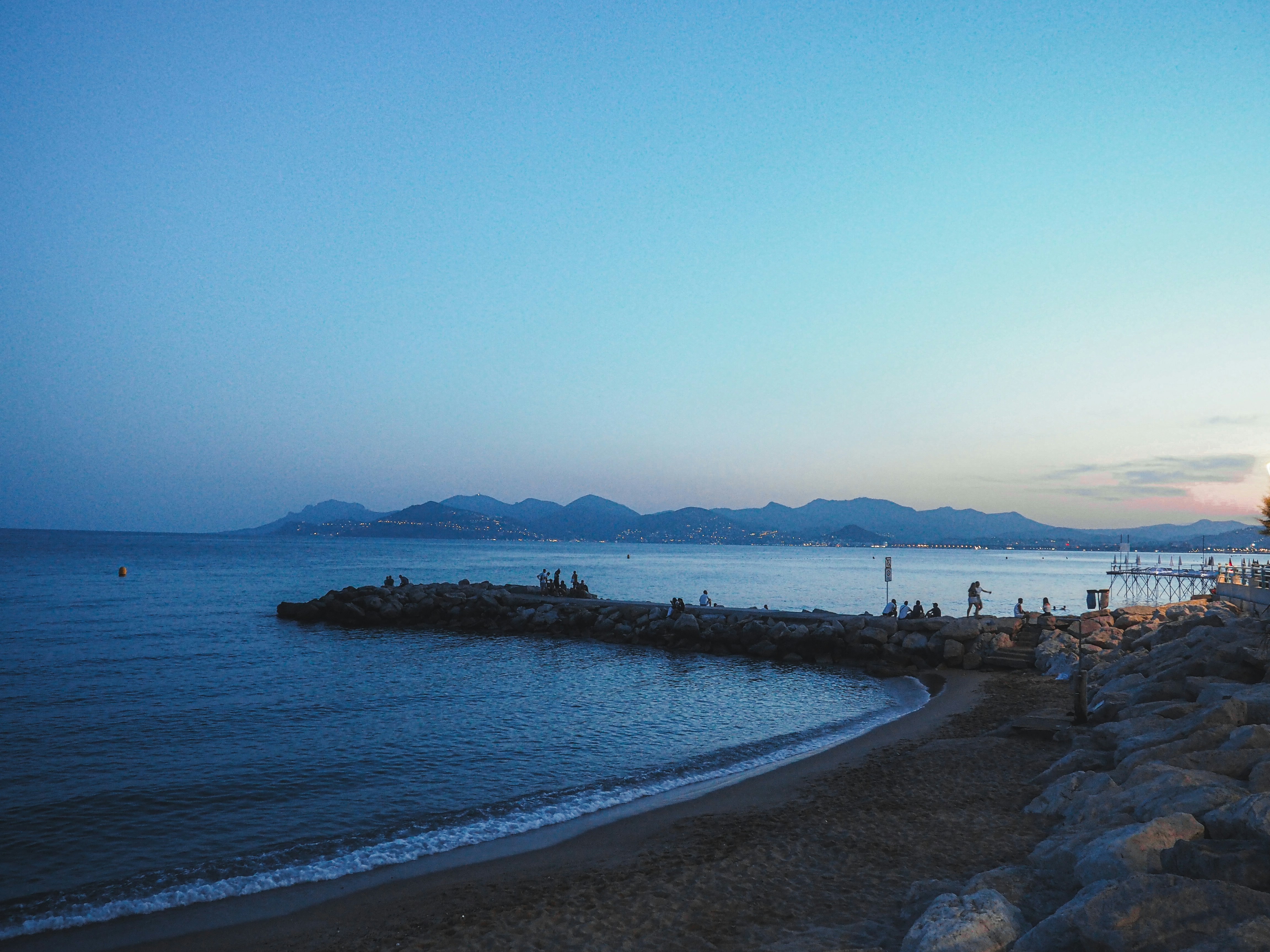 Calm ocean waves lap a sandy beach at dusk.