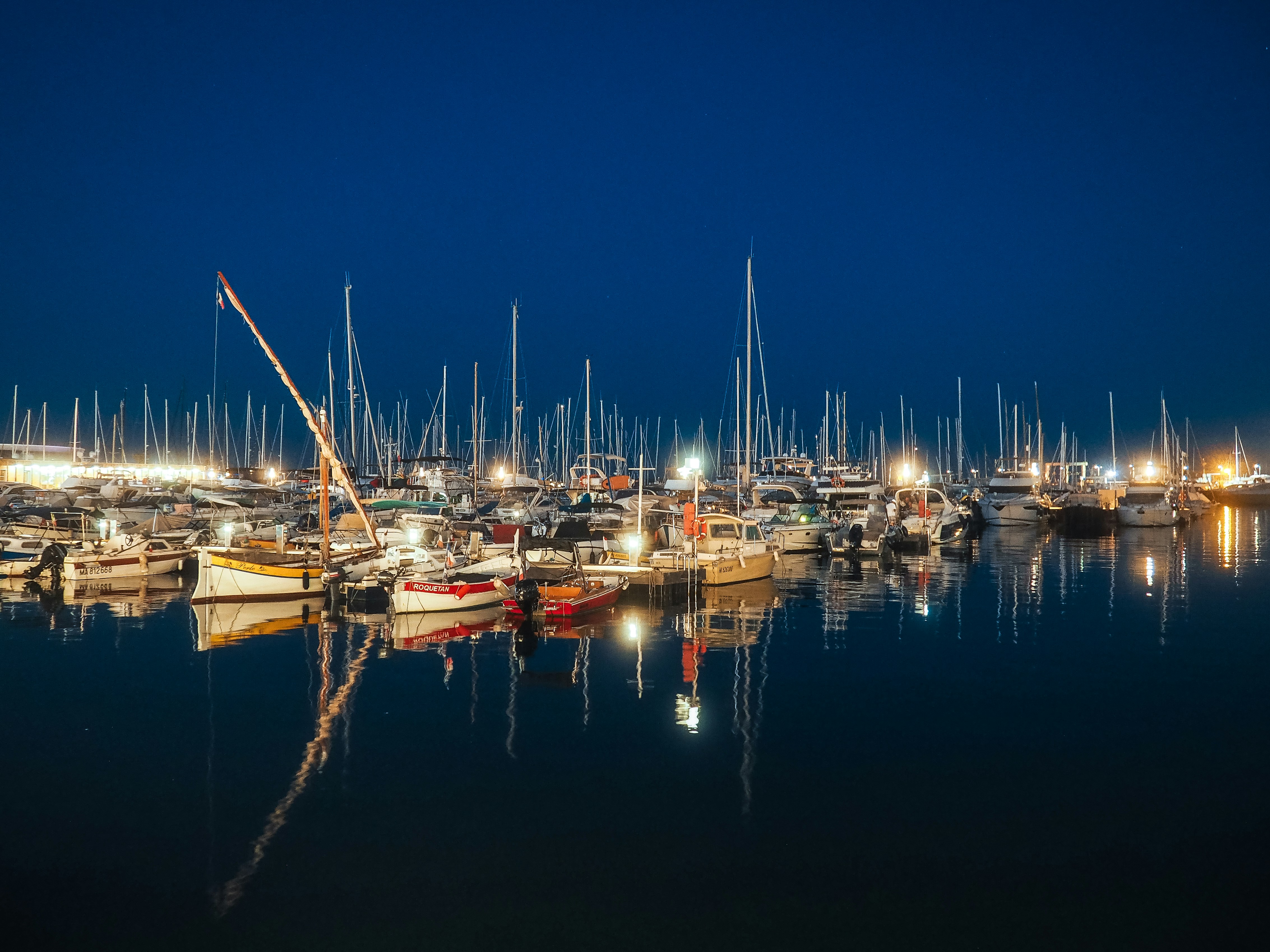Sailboats docked in a harbor at night