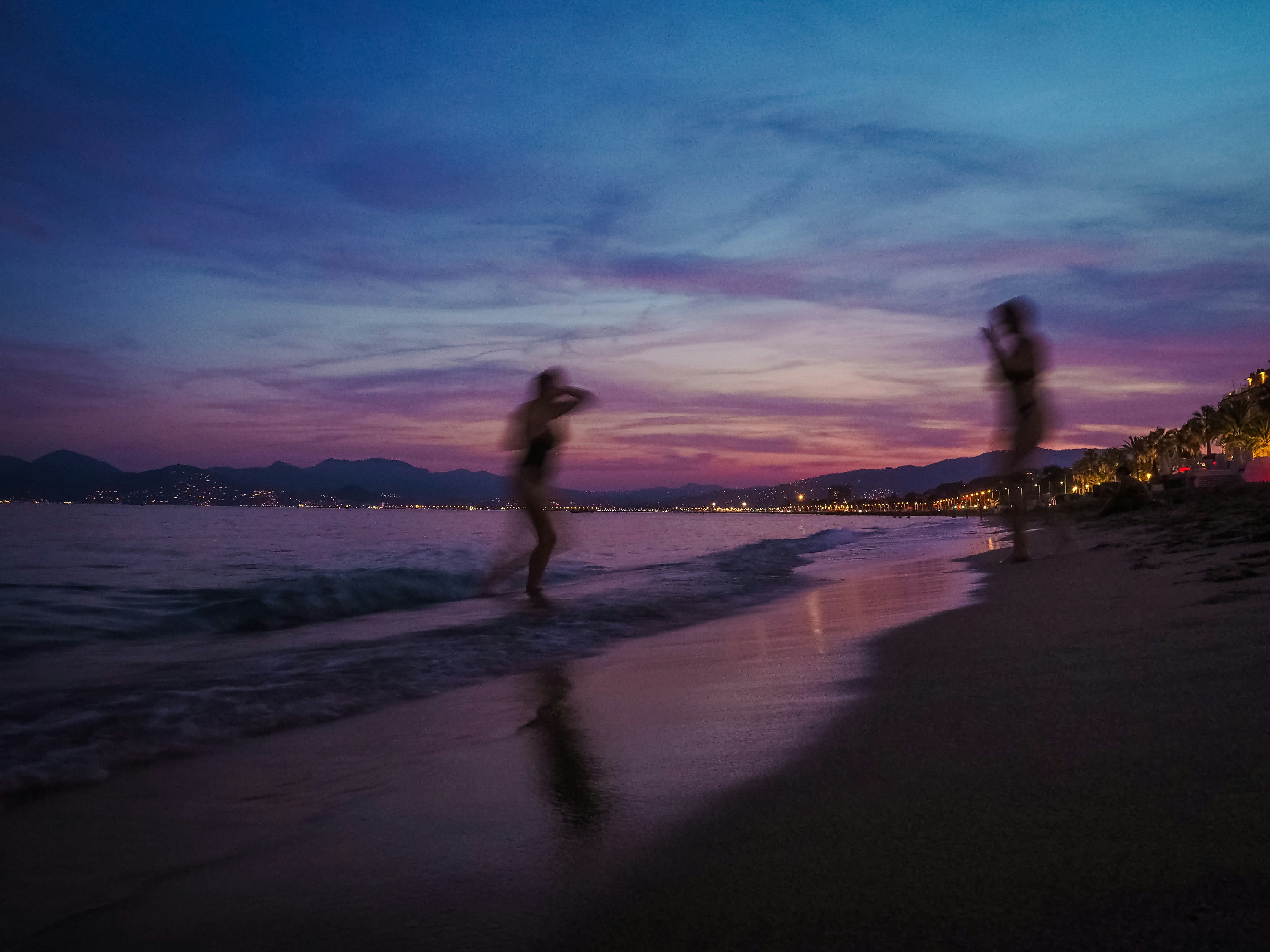 Silhouettes of two people on beach at twilight