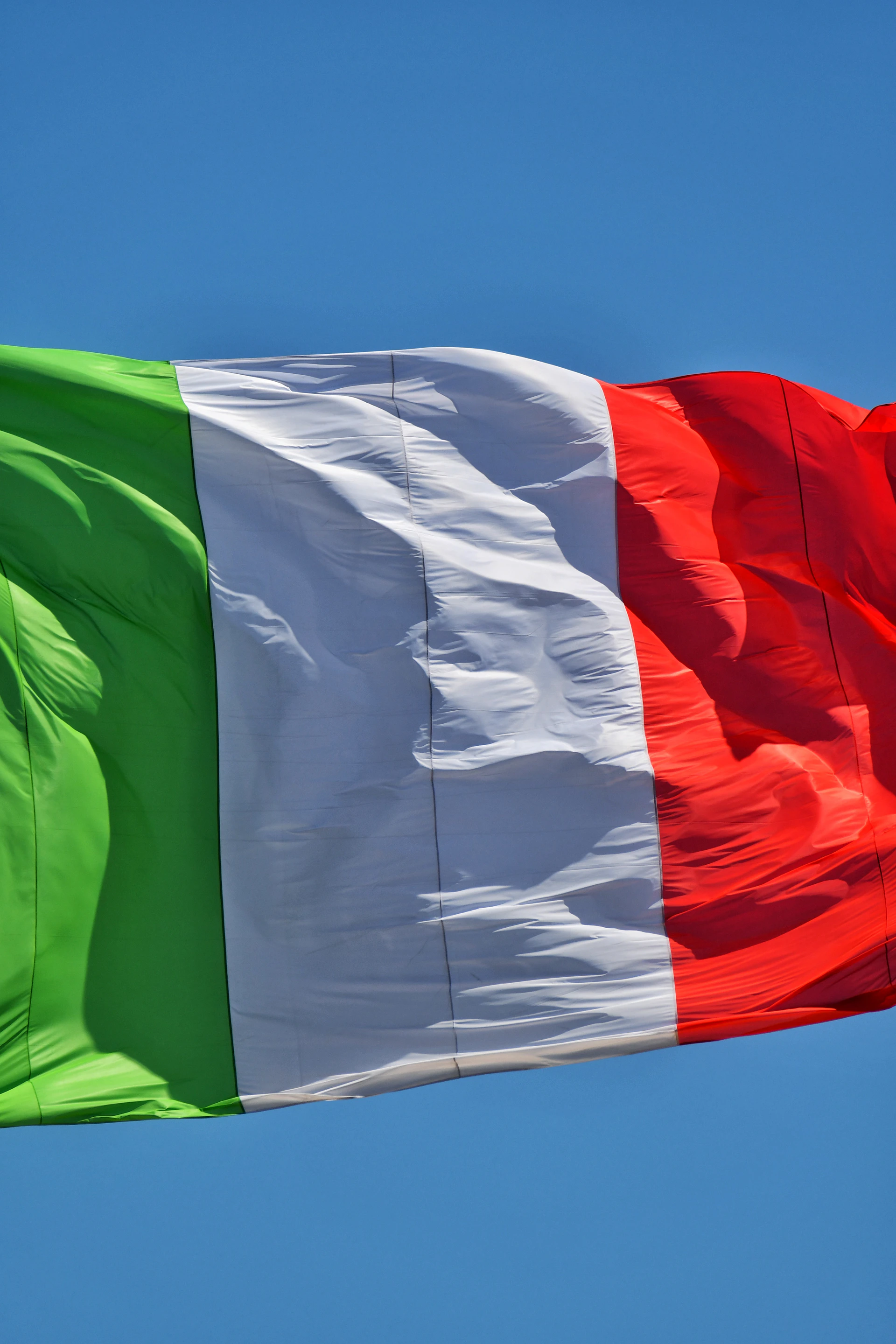Italian flag waving against a clear blue sky