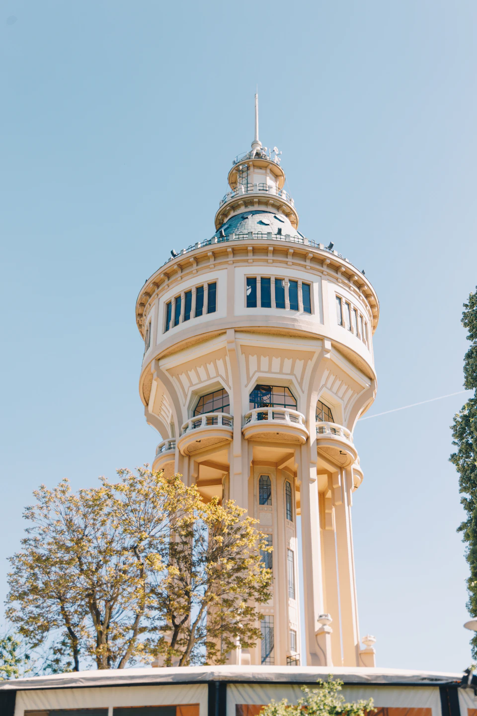 Tall white water tower stands against clear blue sky with pointed roof and dome