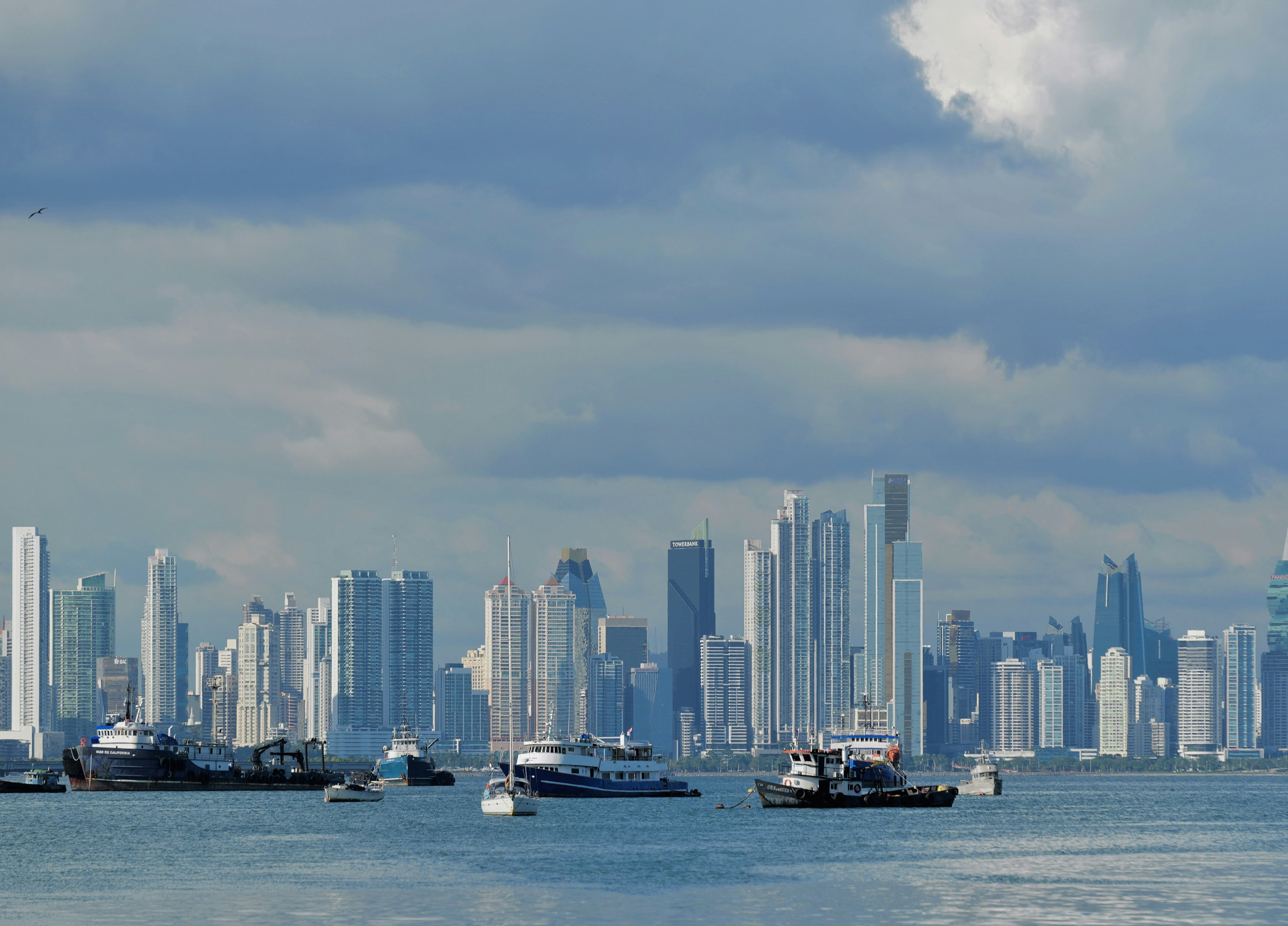 Modern skyscrapers rise above a bay with boats.