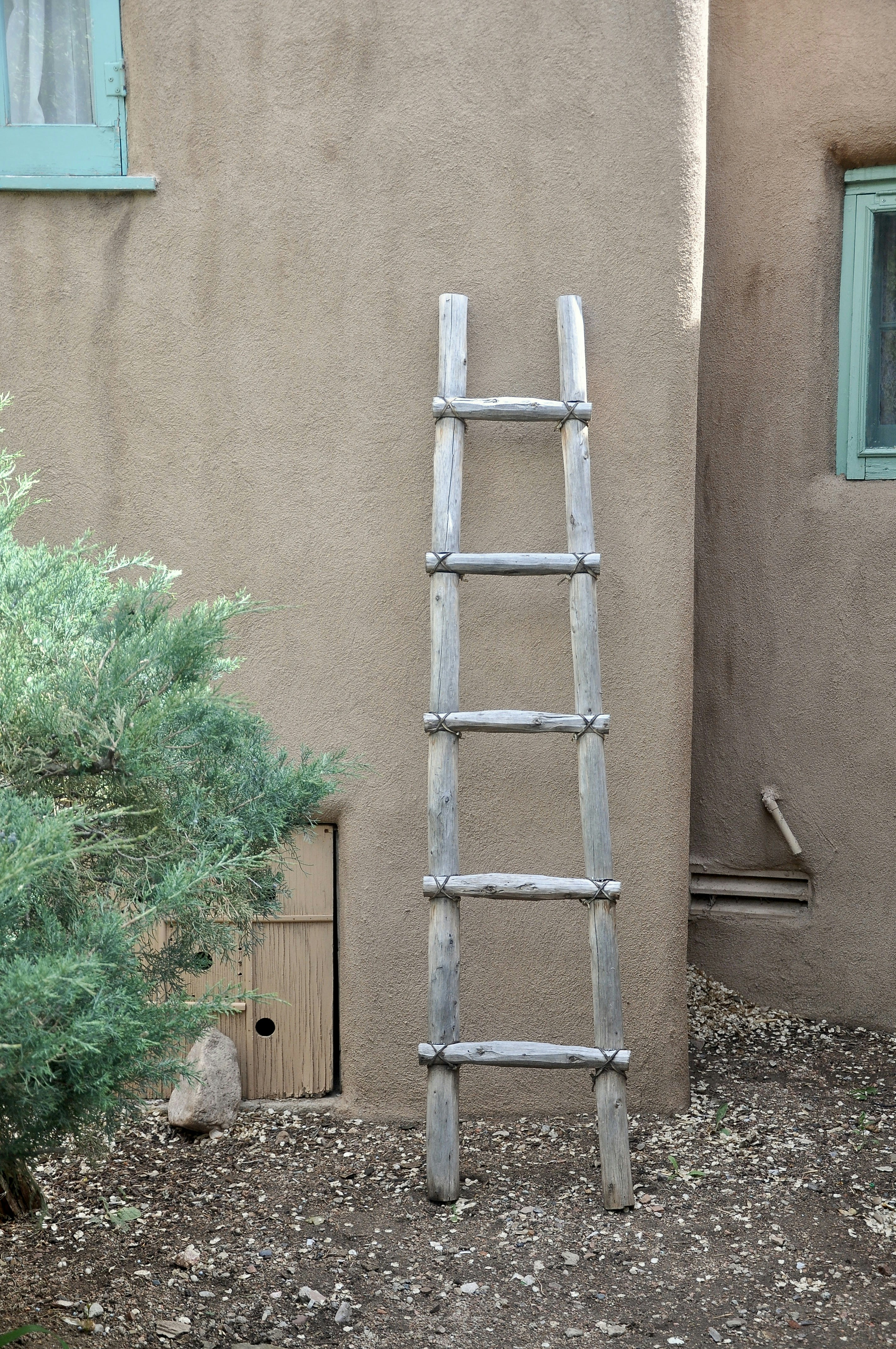 Wooden ladder leaning against adobe wall