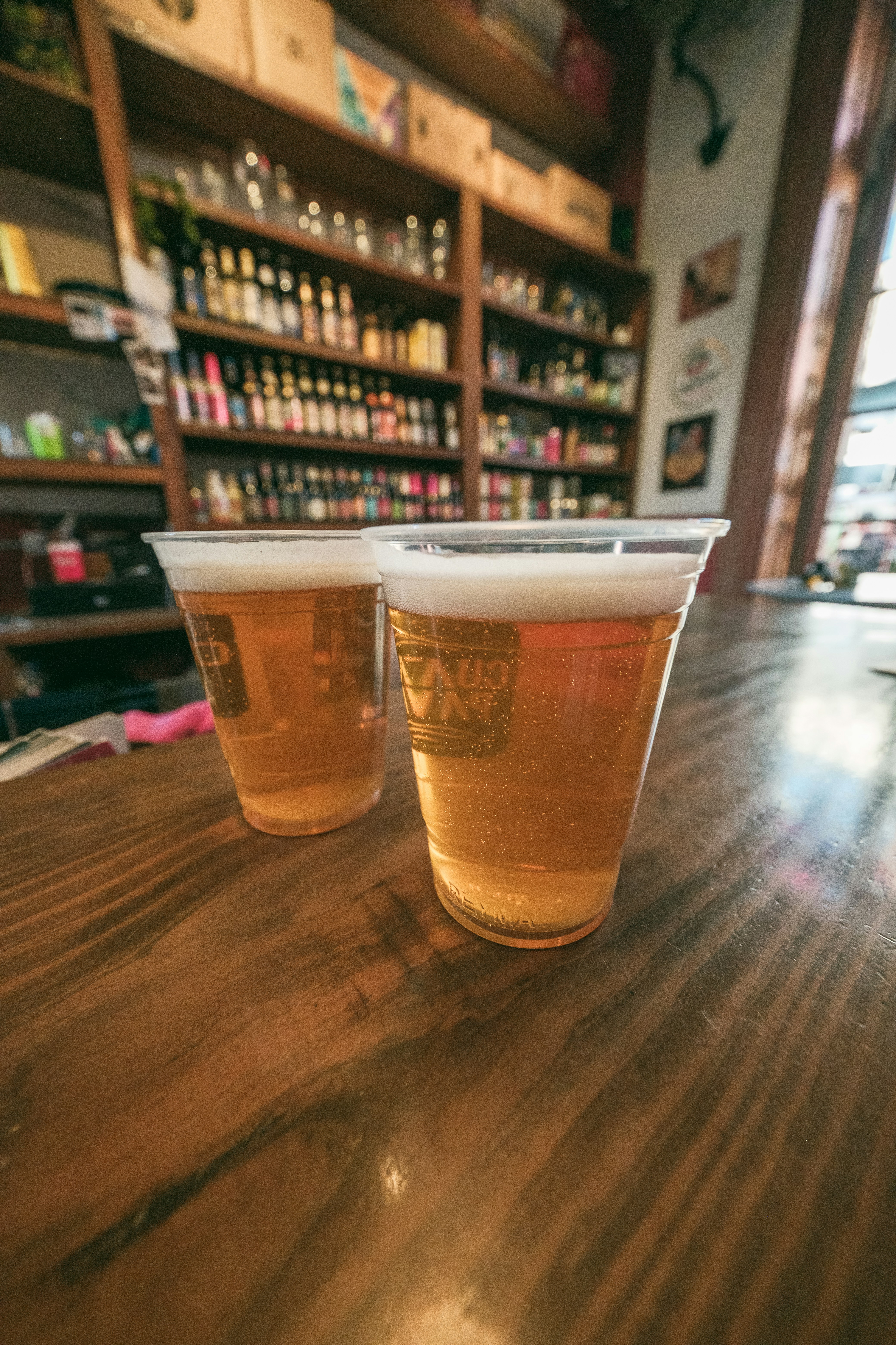 木製のバーの上にプラスチックのビールカップが二つ。