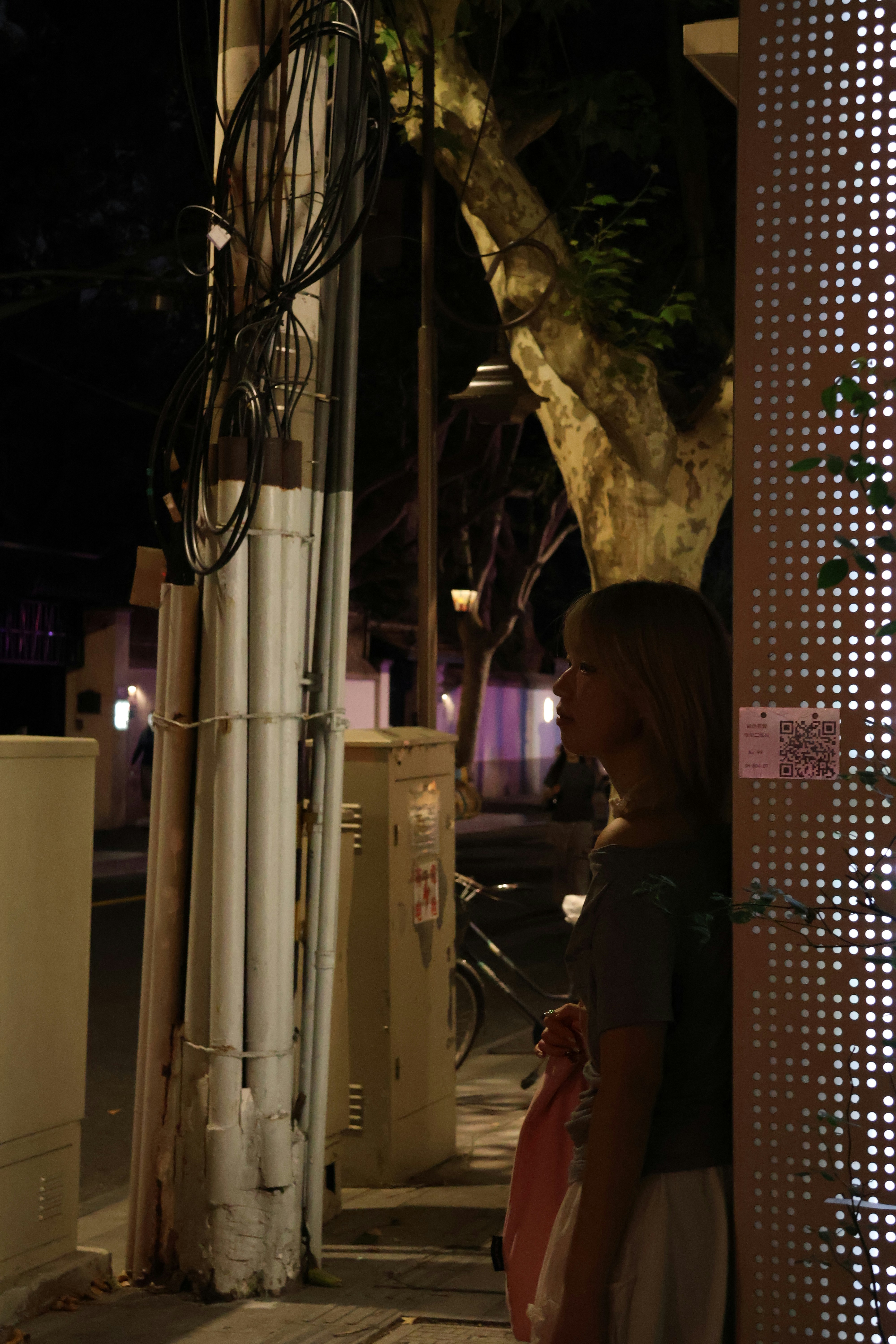 Woman standing by a wall at night