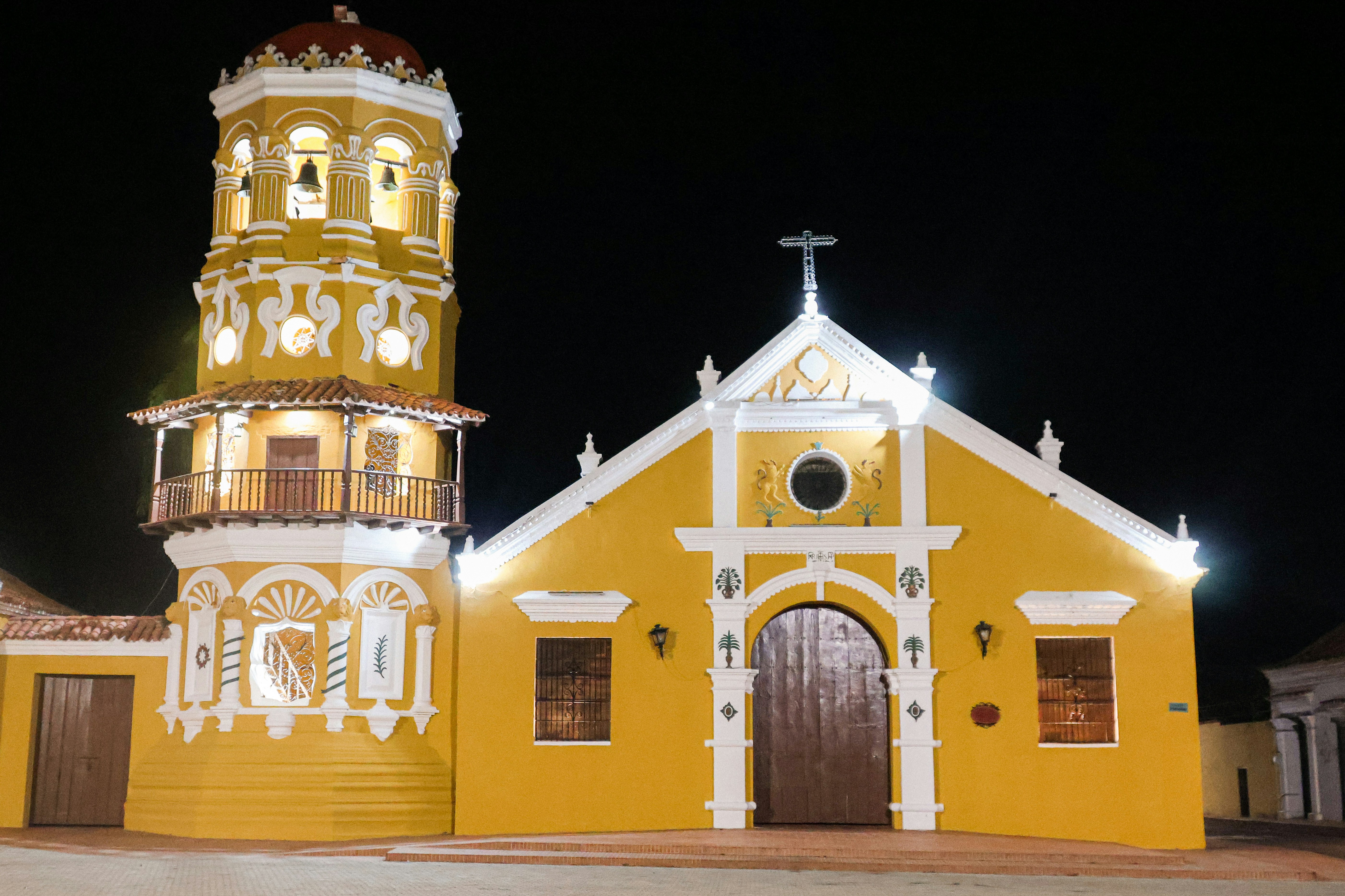Sebuah gereja kuning dengan menara lonceng tinggi di malam hari