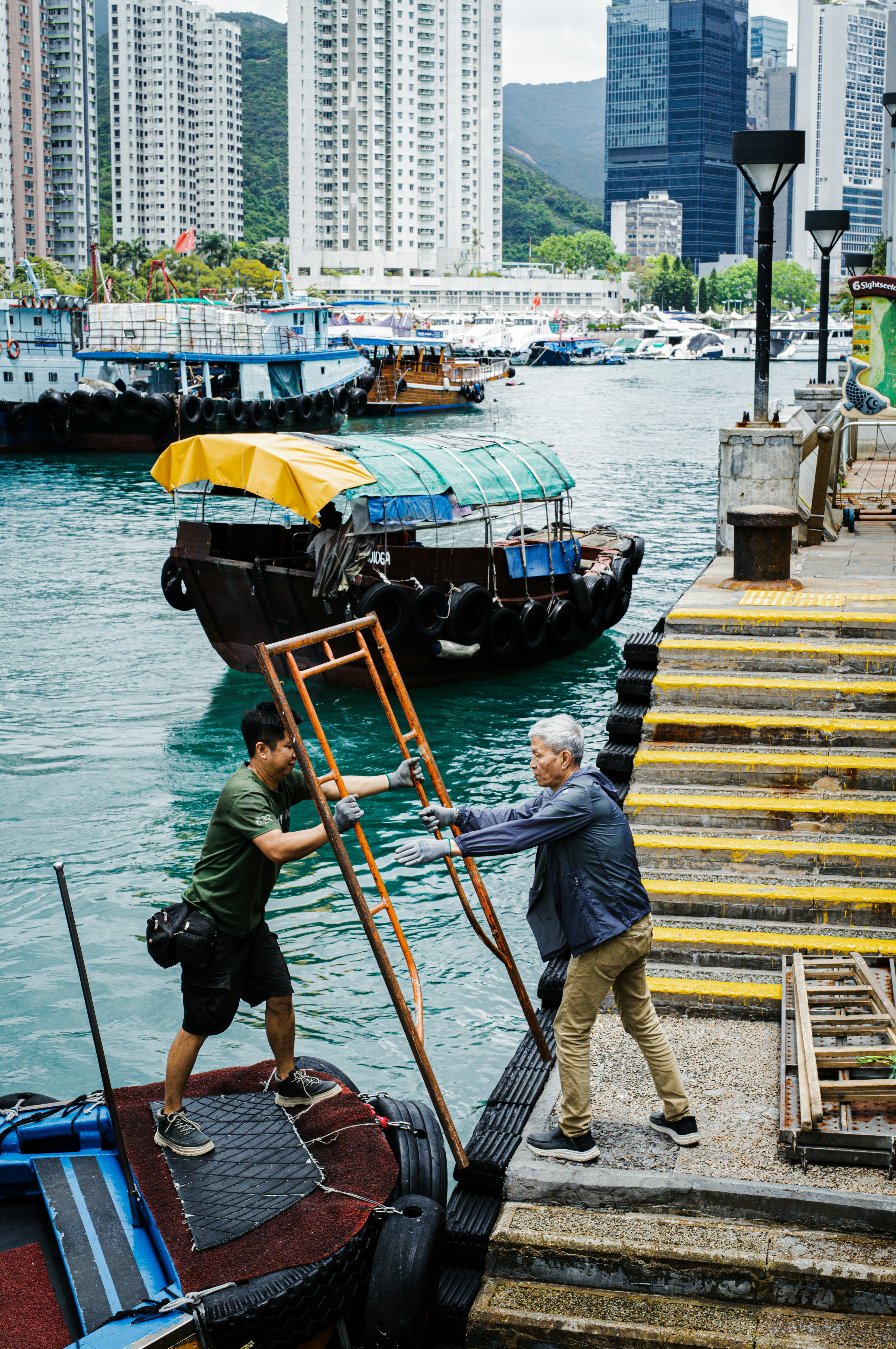 Dois homens carregam uma escada em um barco.