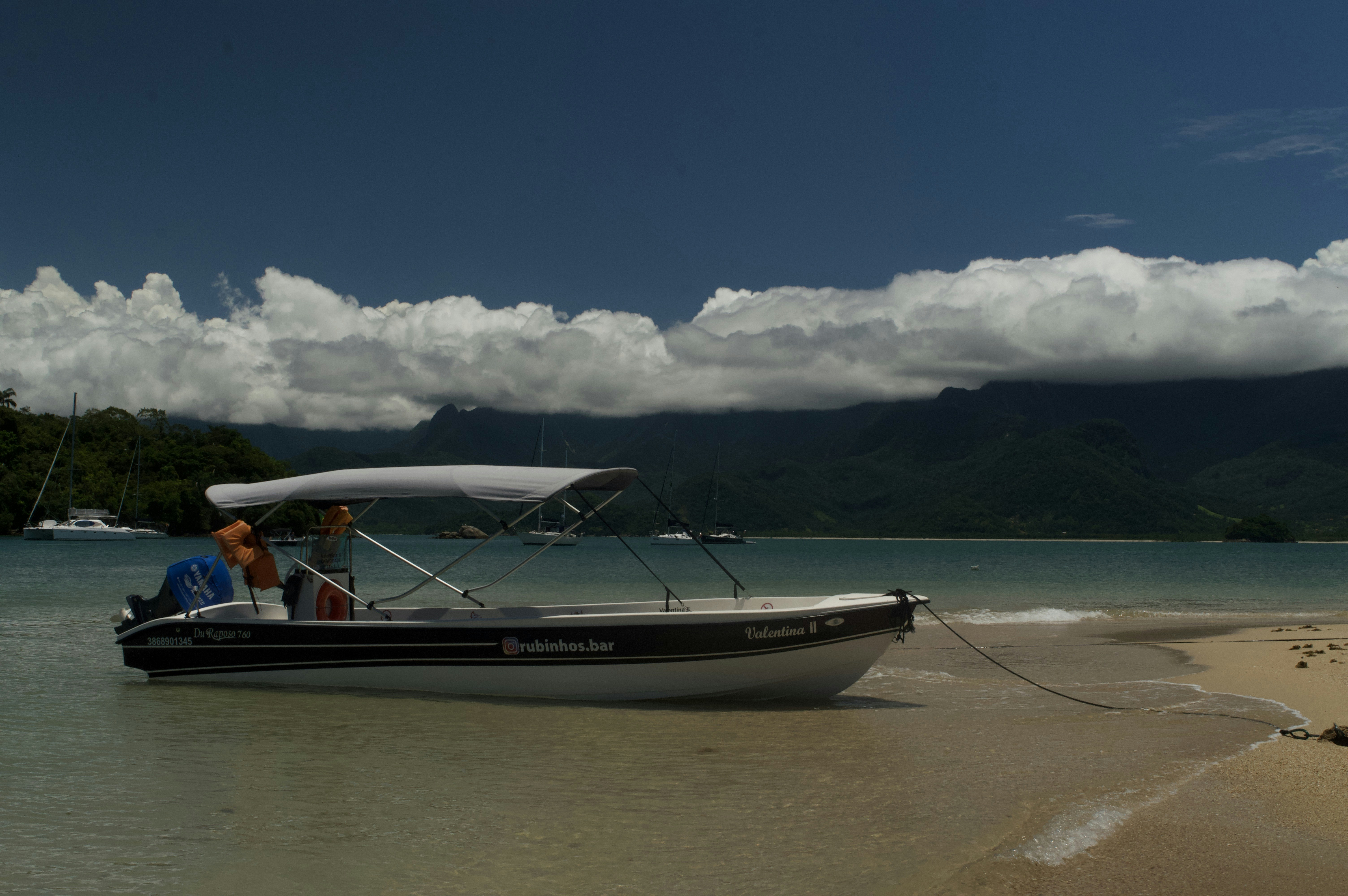 A motorboat rests on a sandy beach by the ocean.