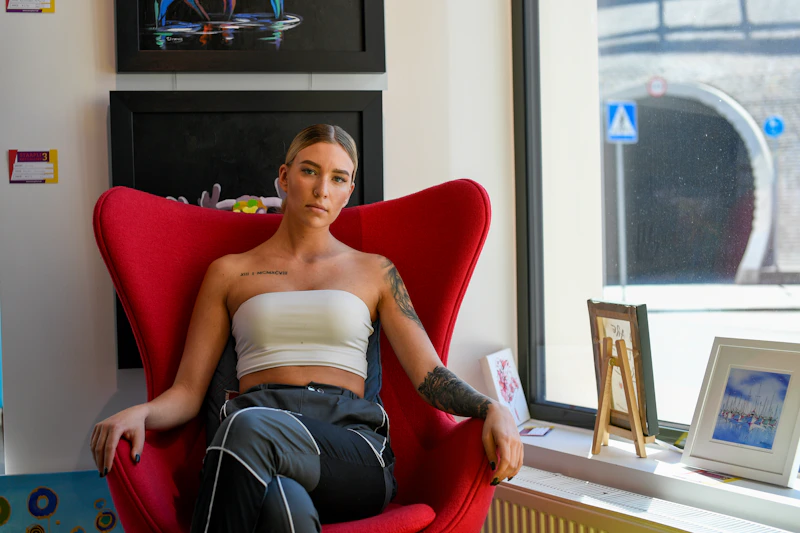 woman sitting in a red chair by a bright window