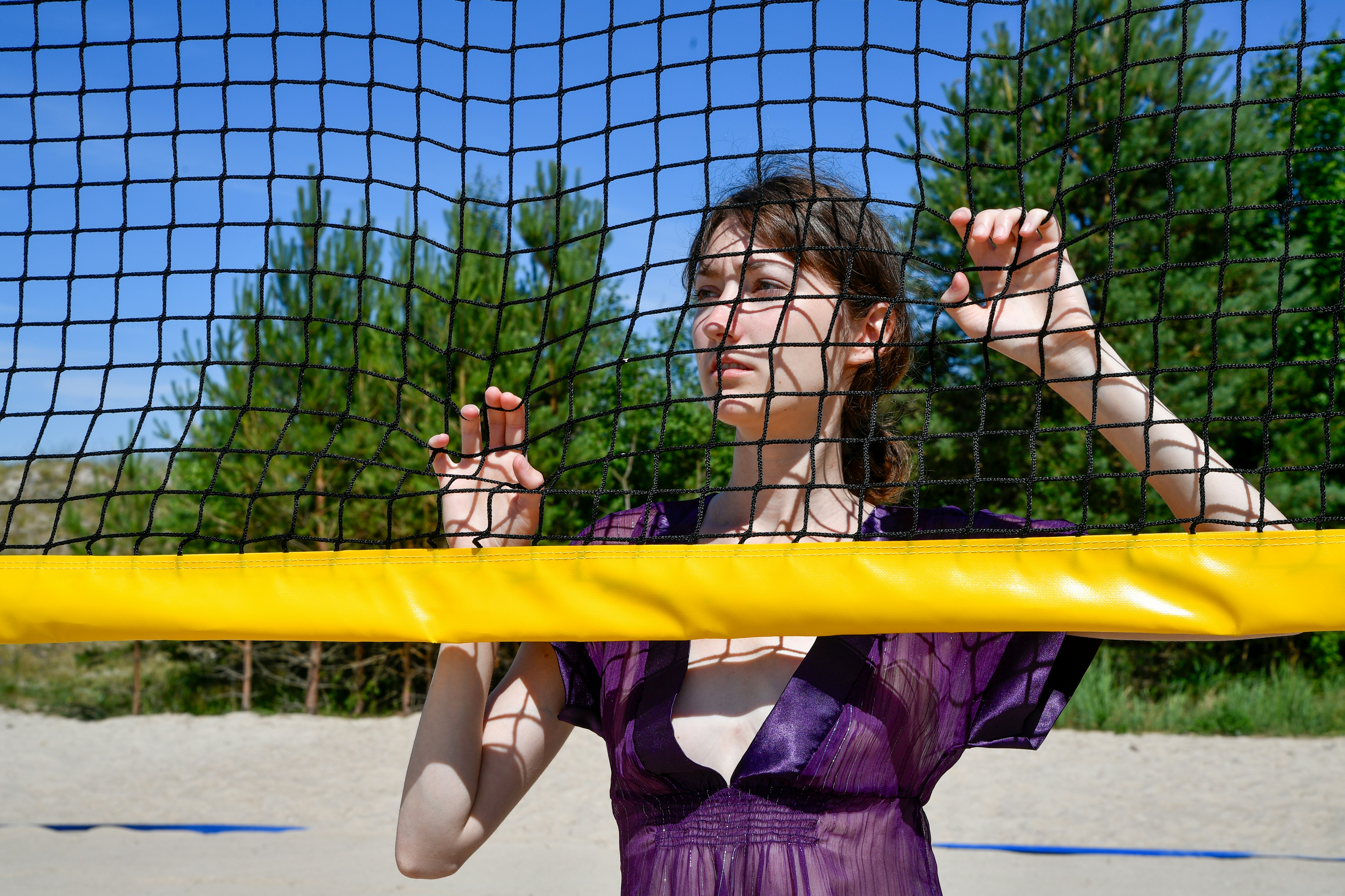 Young woman behind a volleyball net on a sunny day