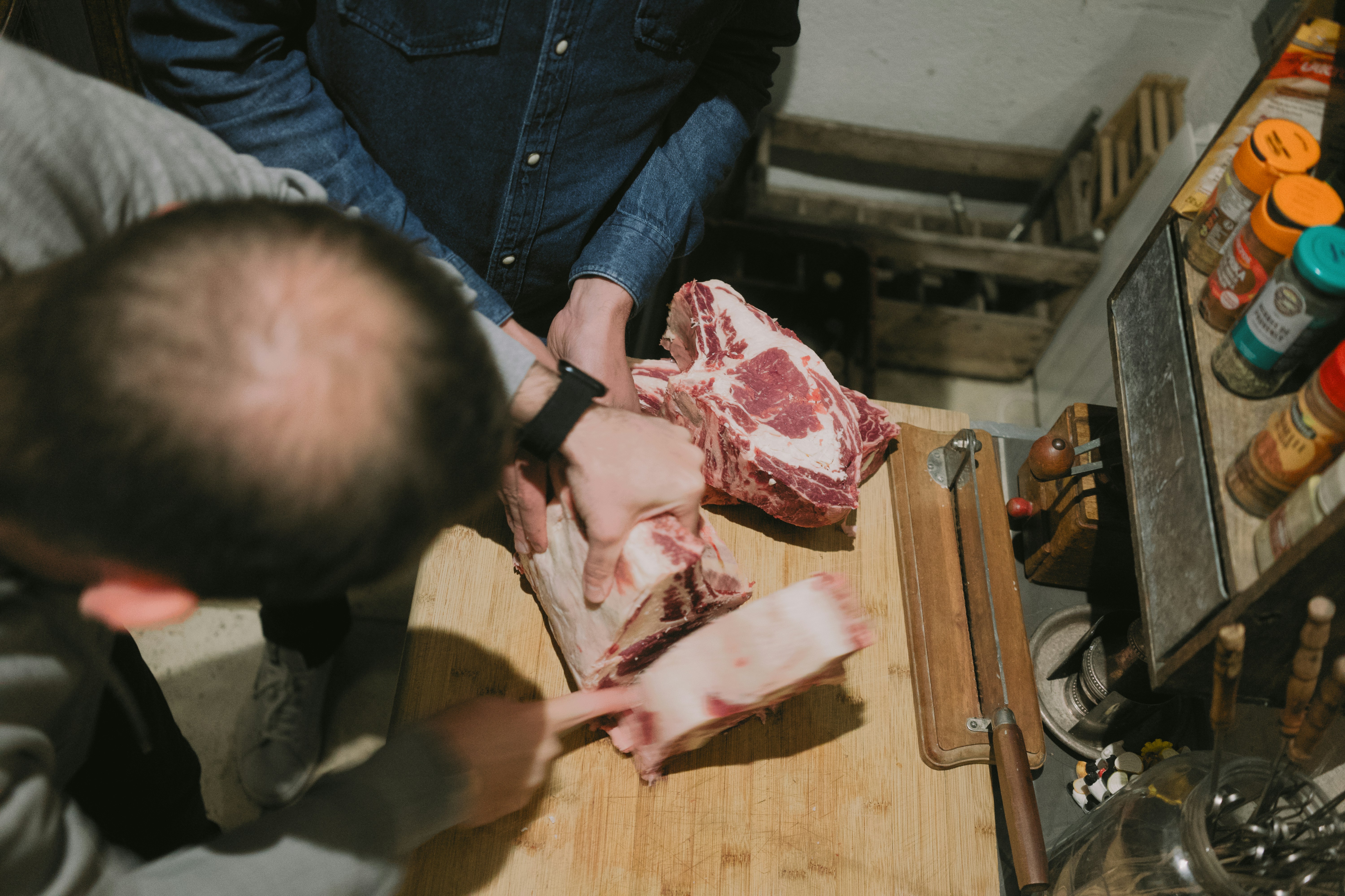 Carnicero preparando cortes de carne cruda sobre tabla de madera.