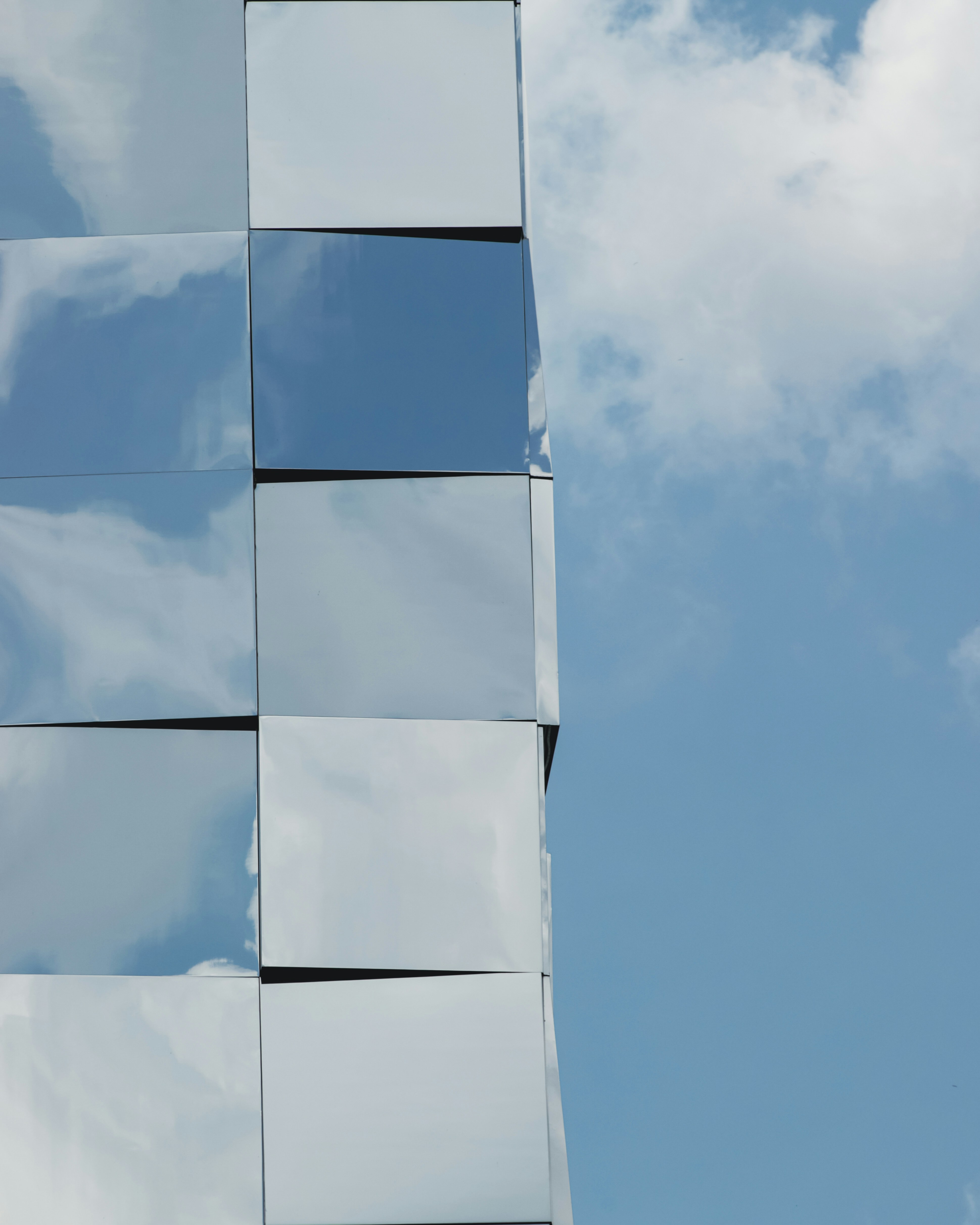 Spiegelnde Gebäudefassade vor blauem Himmel