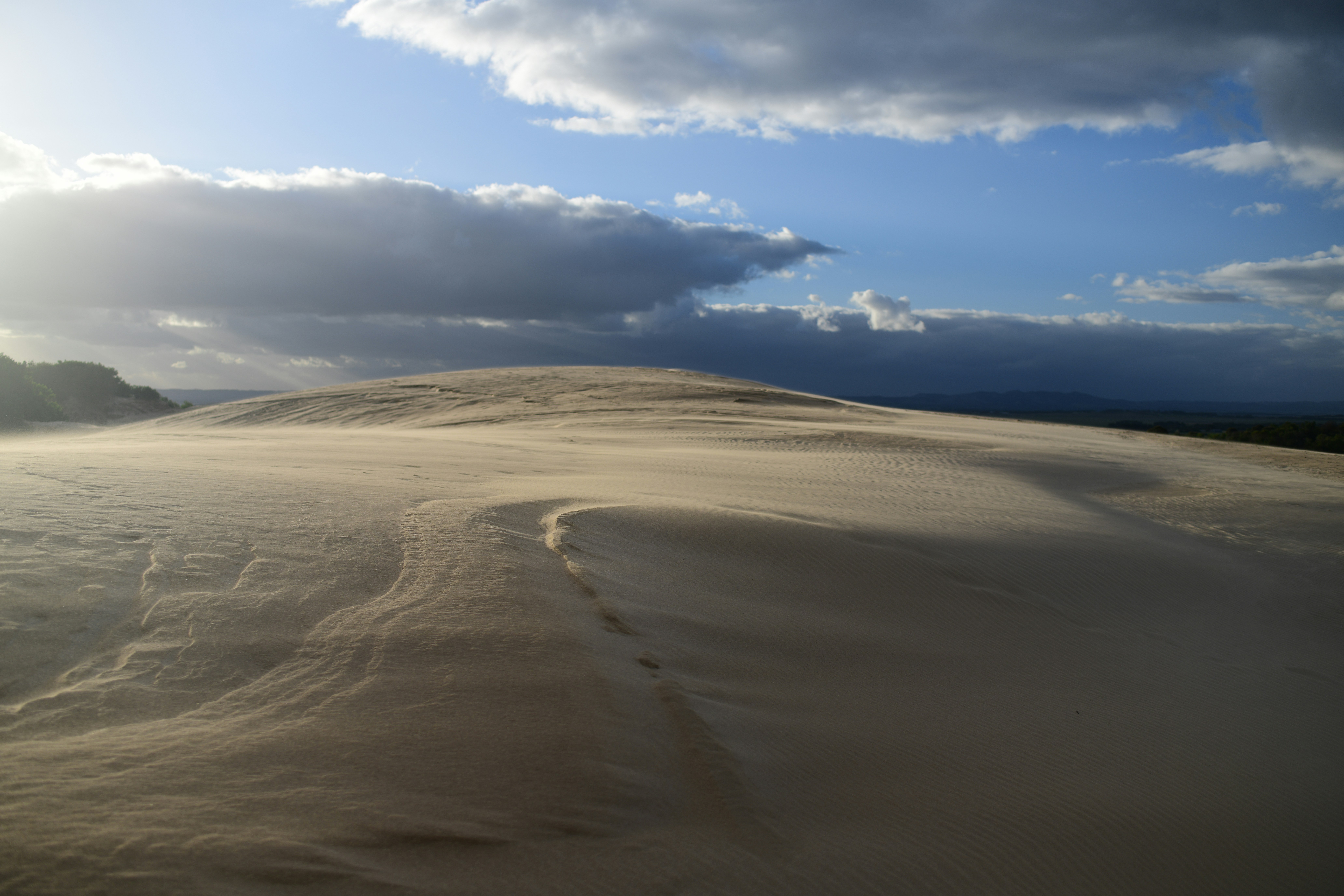 Dune di sabbia con impronte sotto un cielo nuvoloso