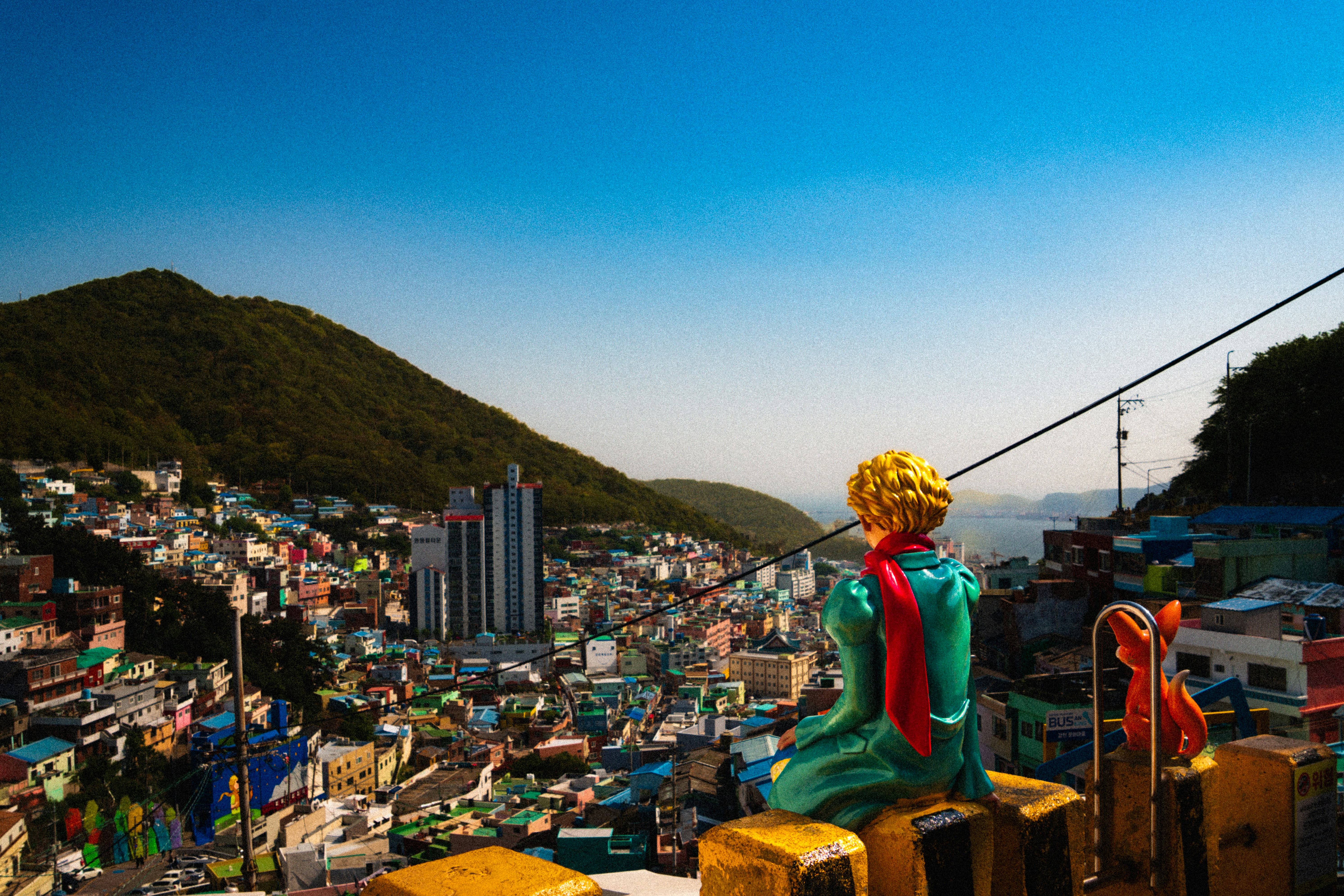 Colorful village nestled in a hillside with a statue.