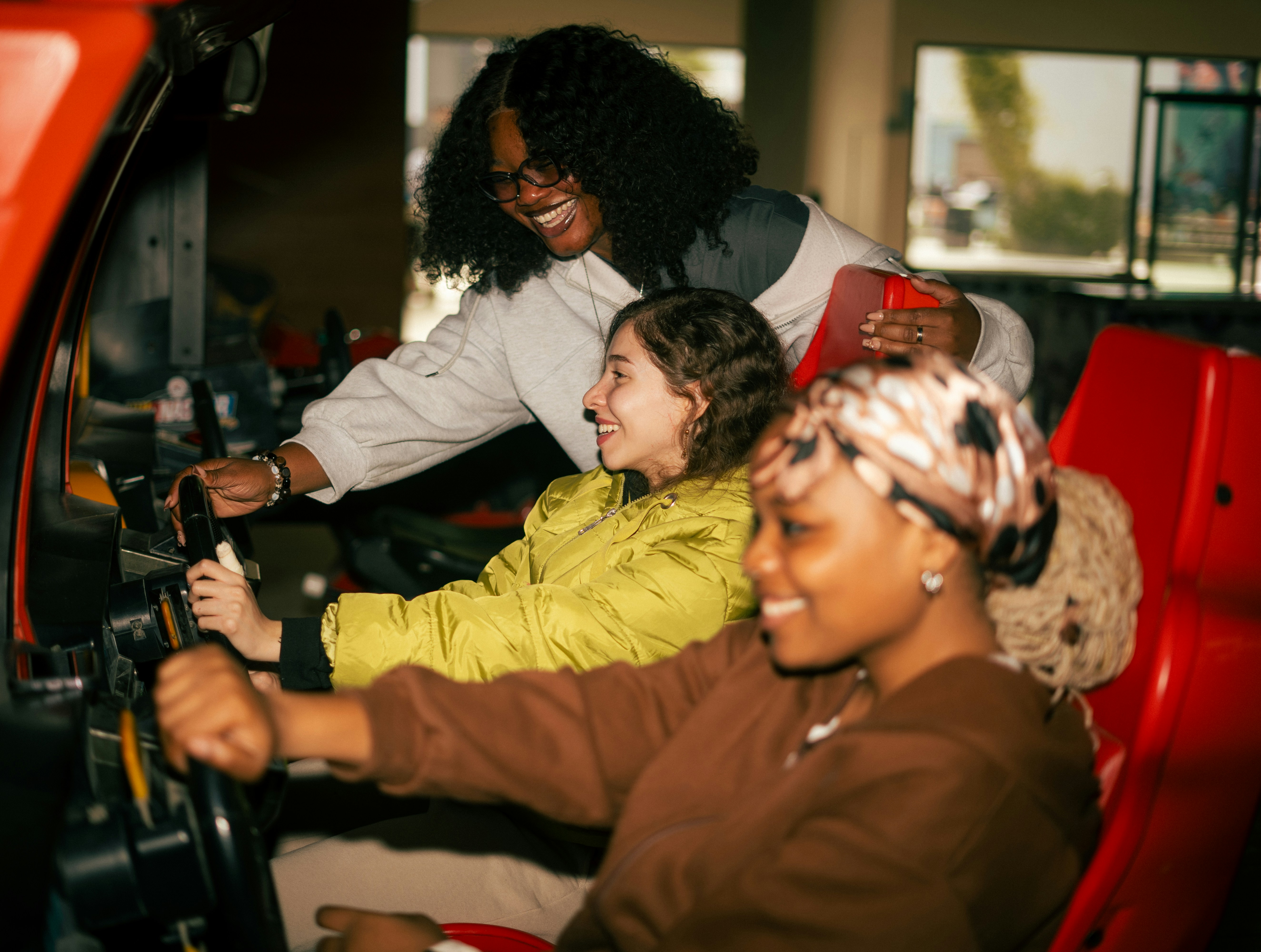 Trois amis jouant ensemble à un jeu d’arcade de course