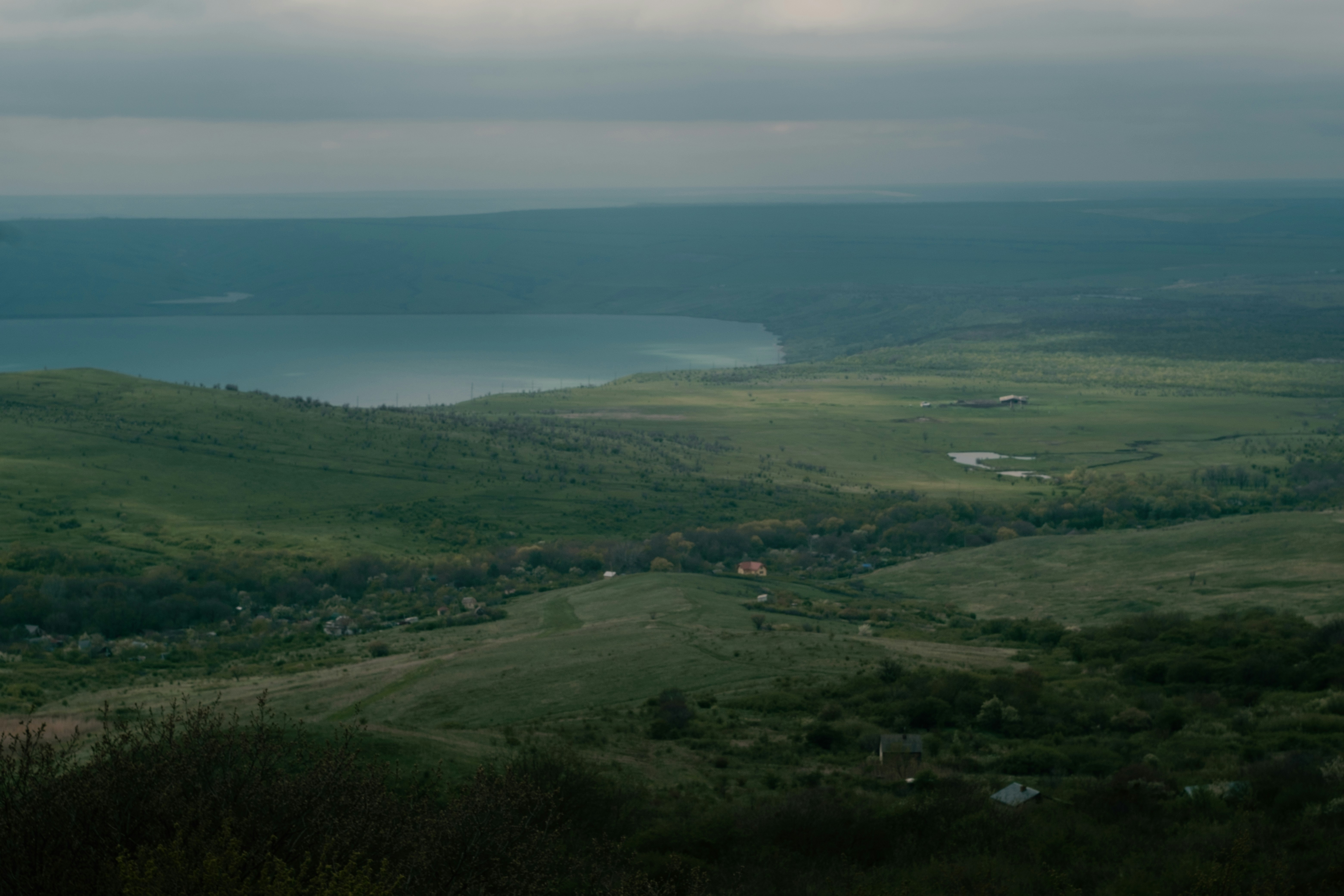 Rolling green hills meet a misty distant lake